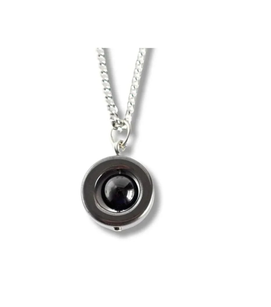 A black and silver necklace with a circular pendant containing a black camera lens.