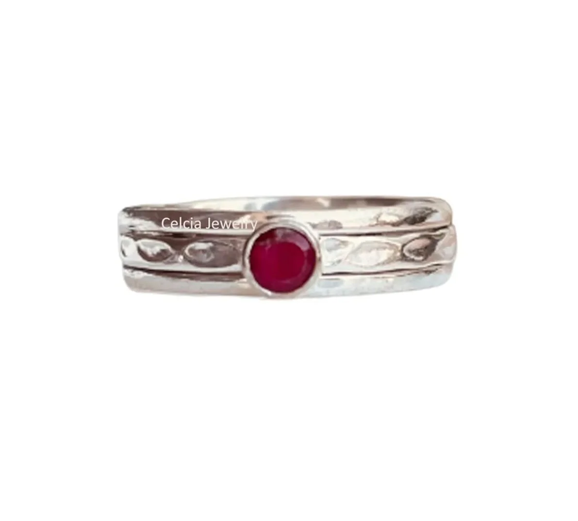 Silver ring with textured band and a central red gemstone, branded with 'Celcia Jewelry'.