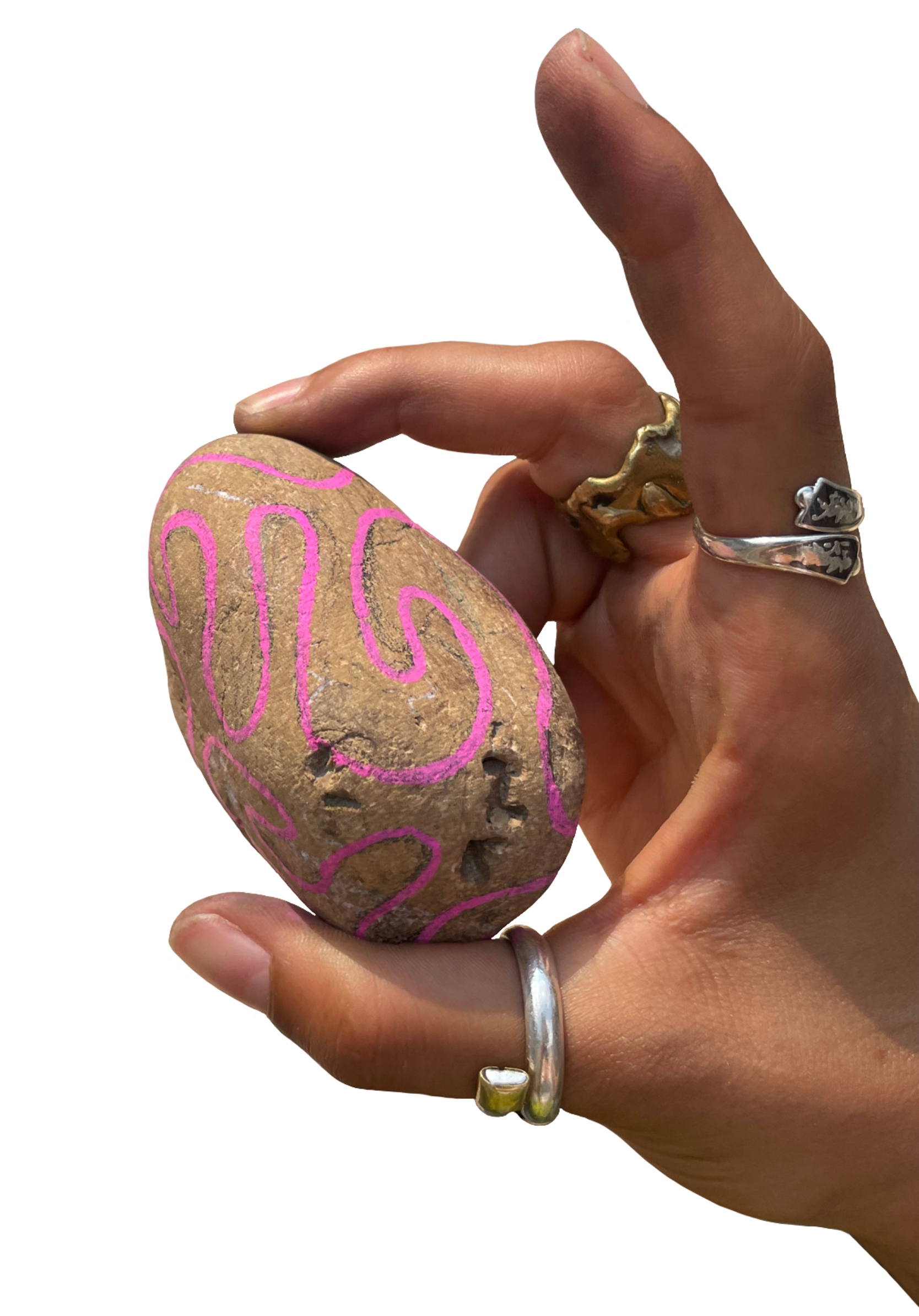 A hand with rings holding a painted rock with pink squiggles on it.