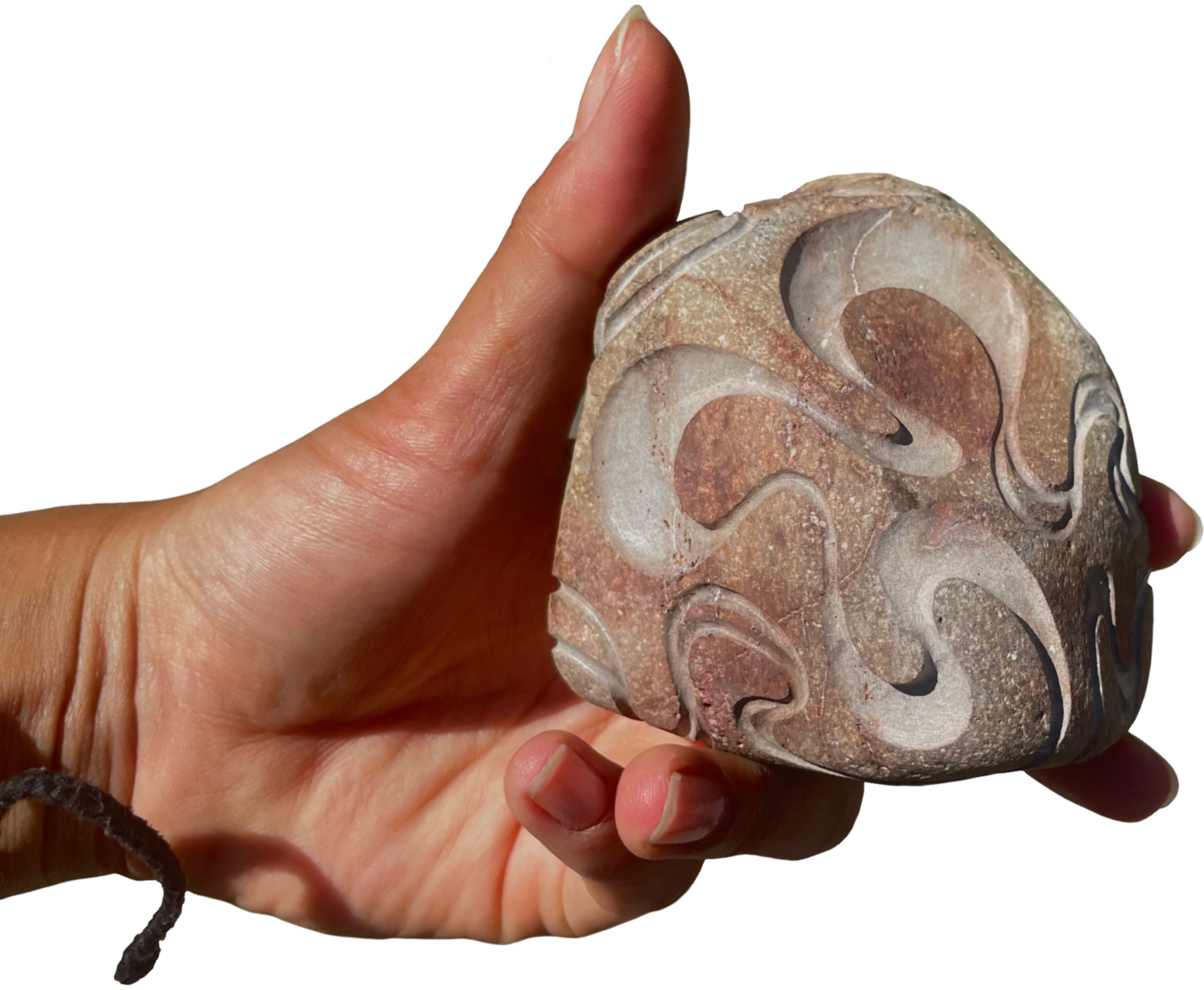 A person holding a carved stone with swirling patterns.