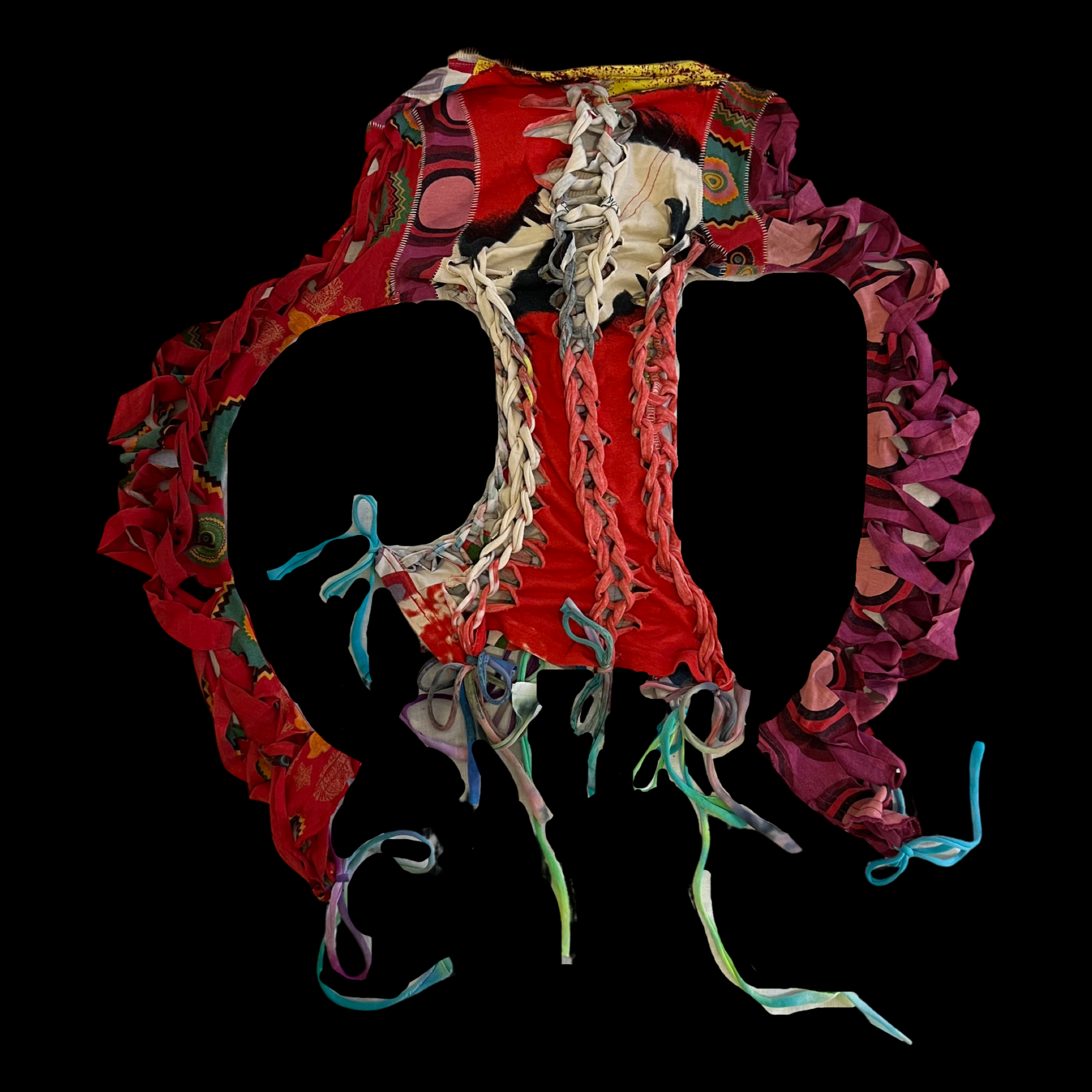 A colorful patchwork quilt crafted in the shape of a peace symbol, with various ribbons tied around the edges.