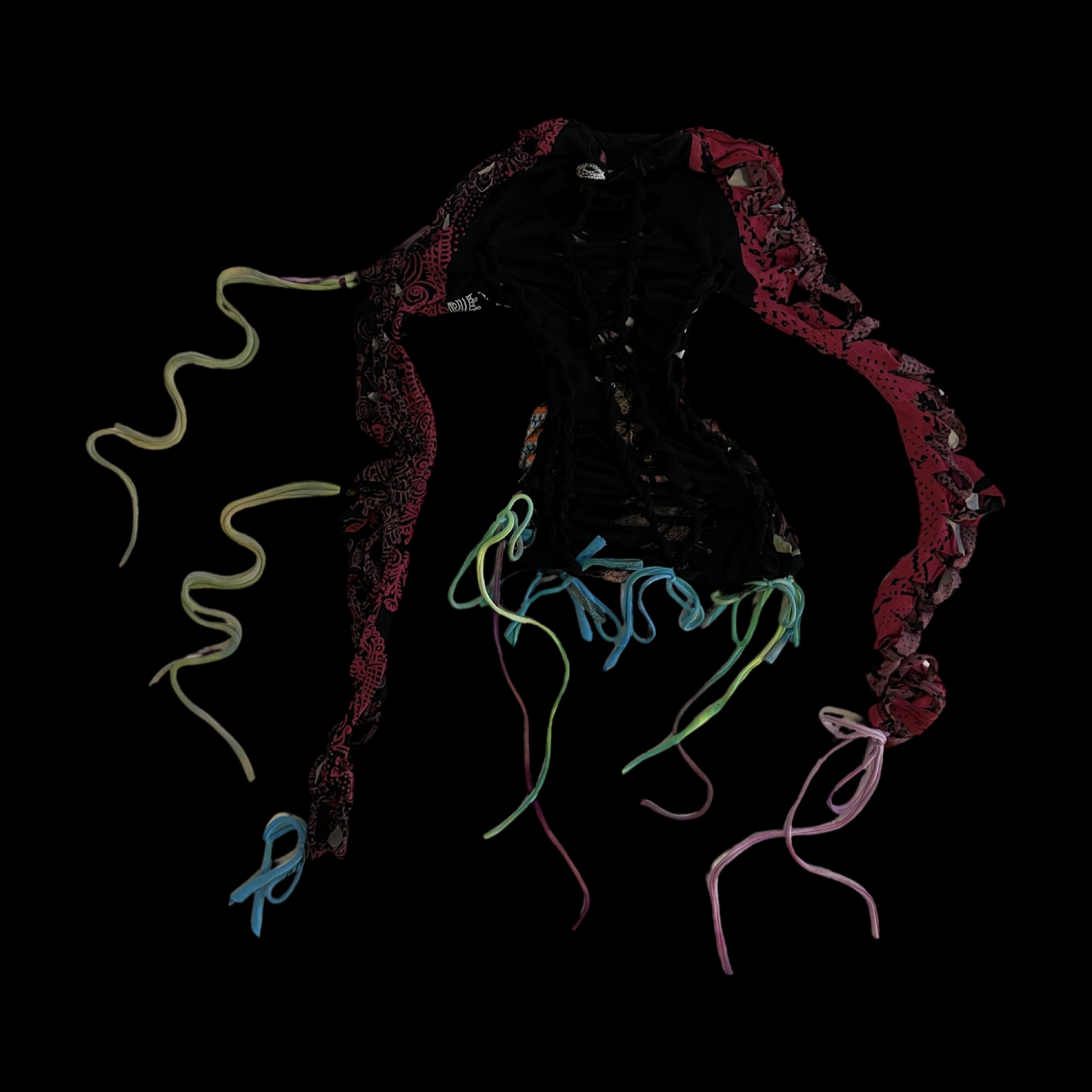 A black dress with colorful patterned fabric trims and multicolored ribbons on a black background.