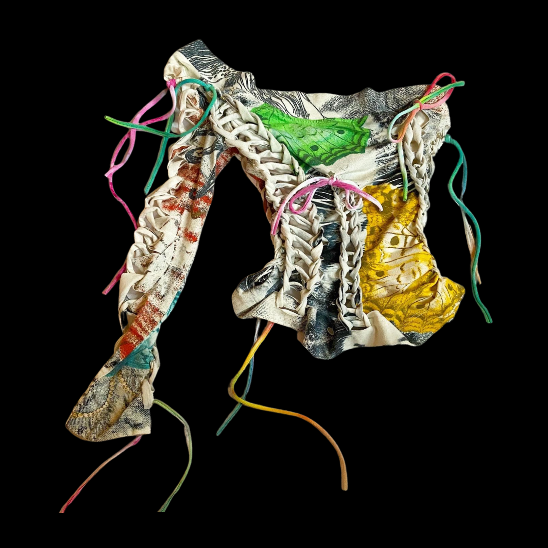 A crumpled fabric item with lace-up details and colorful printed design on a black background.