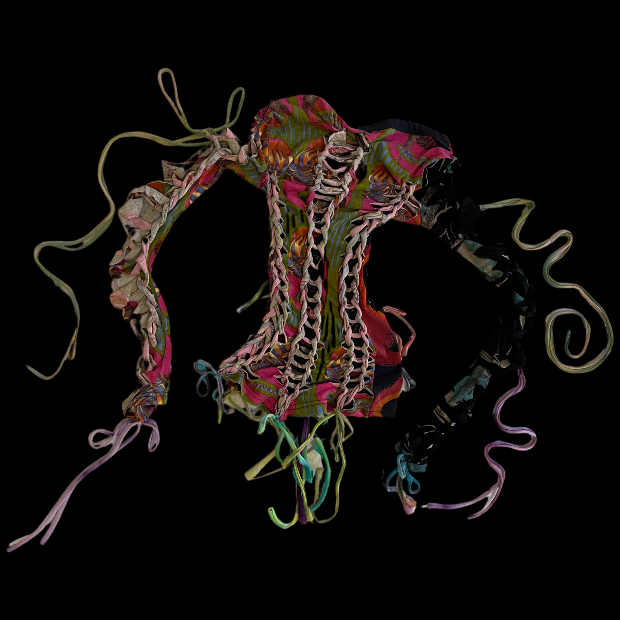 A colorful, intricately laced fabric piece with long, twisted strings, set against a black background.