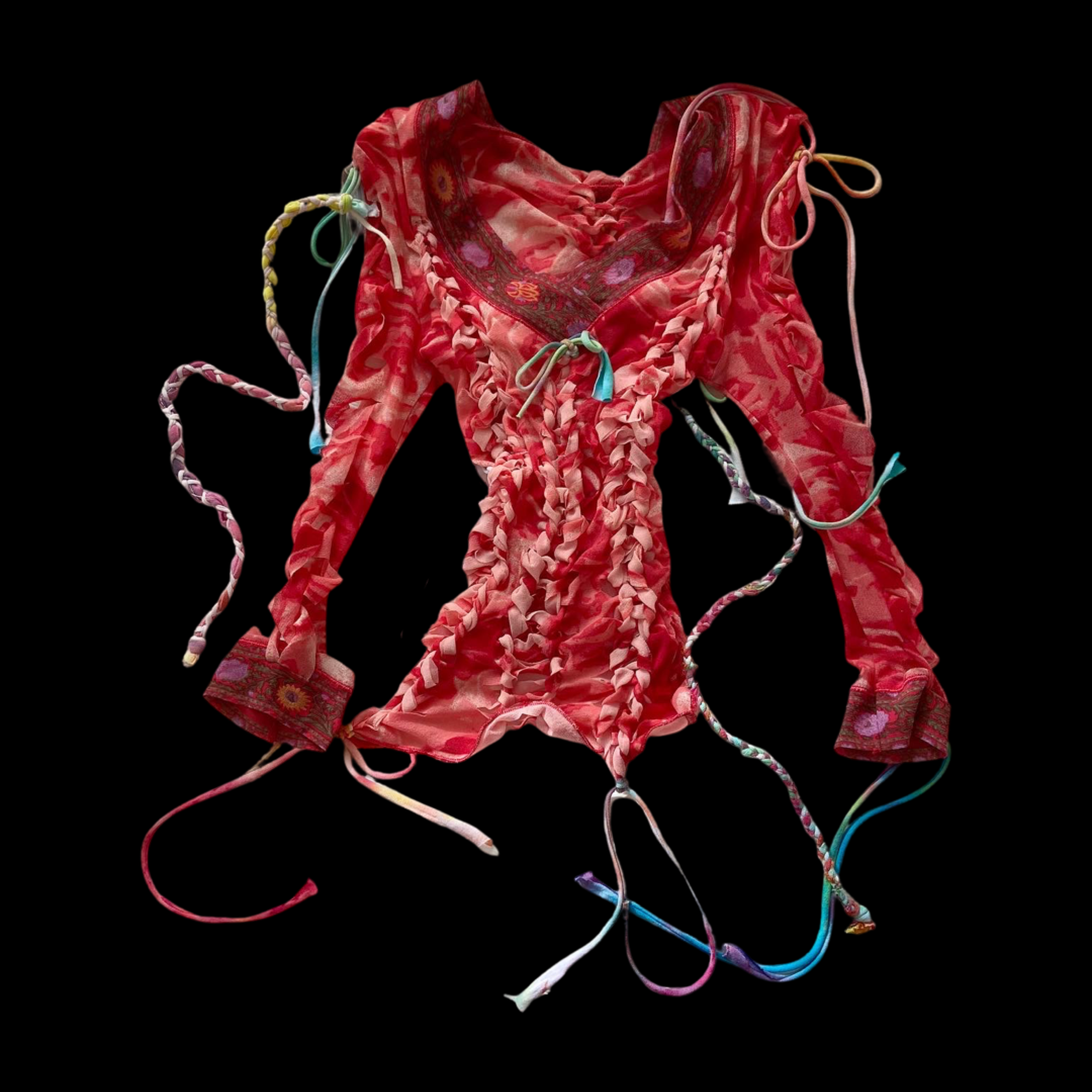 A colorful, ruffled, and embroidered bohemian-style top with multicolored strings hanging from the sleeves and bottom, laid on a black background.