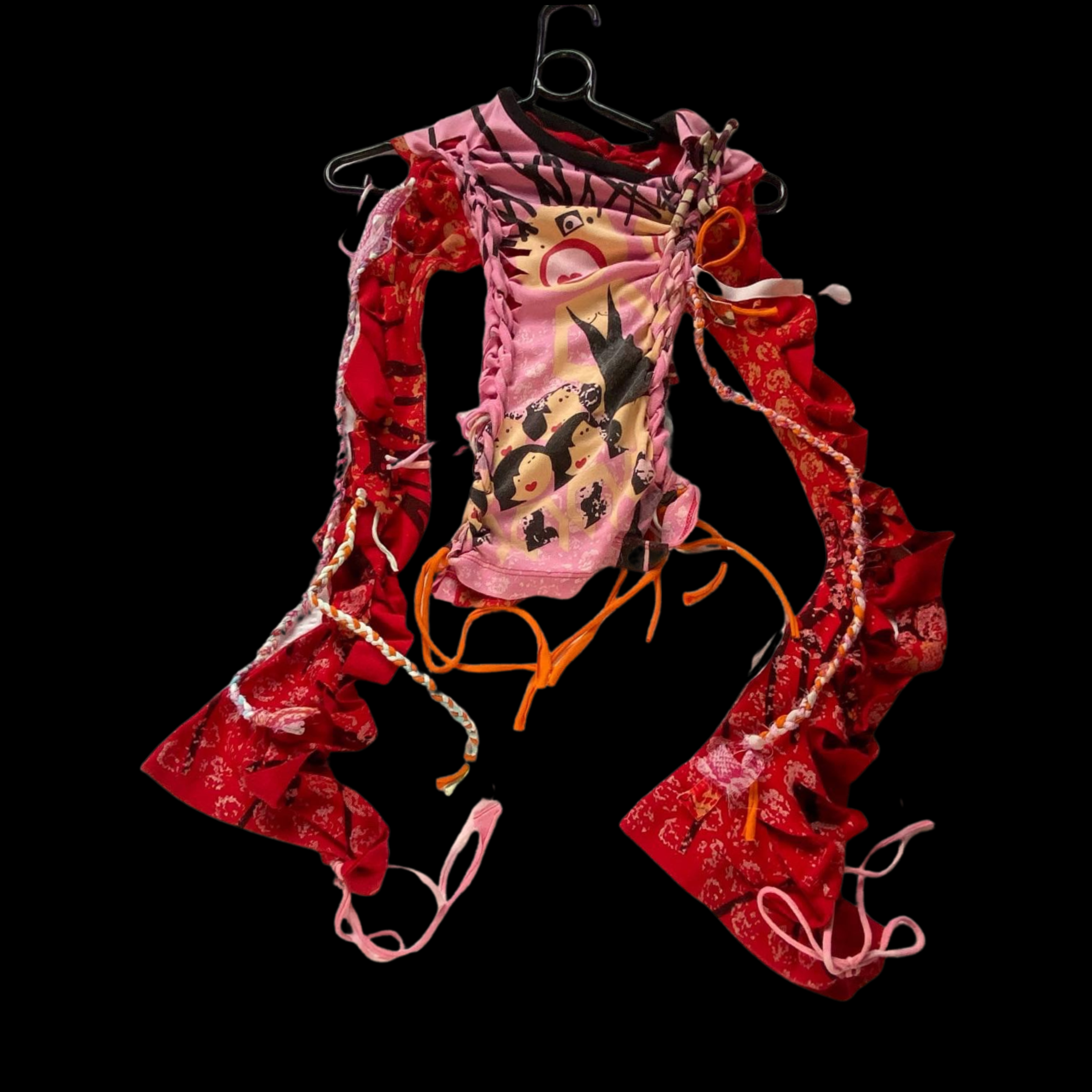A colorful dress with red, pink, and orange fabric, featuring ruffles, bows, and various patterns, hanging on a black background.
