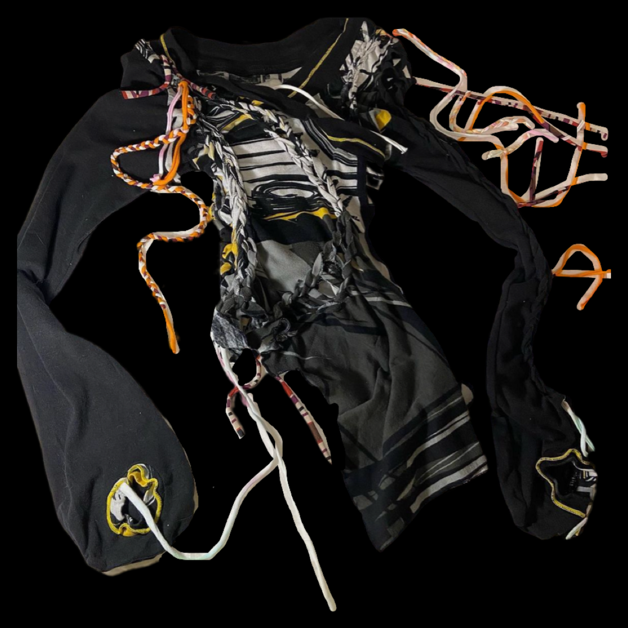 A black patchwork scarf with various fabric patterns, orange, yellow, and white braided and flat laces, and a small embroidered patch with a yellow and black design.