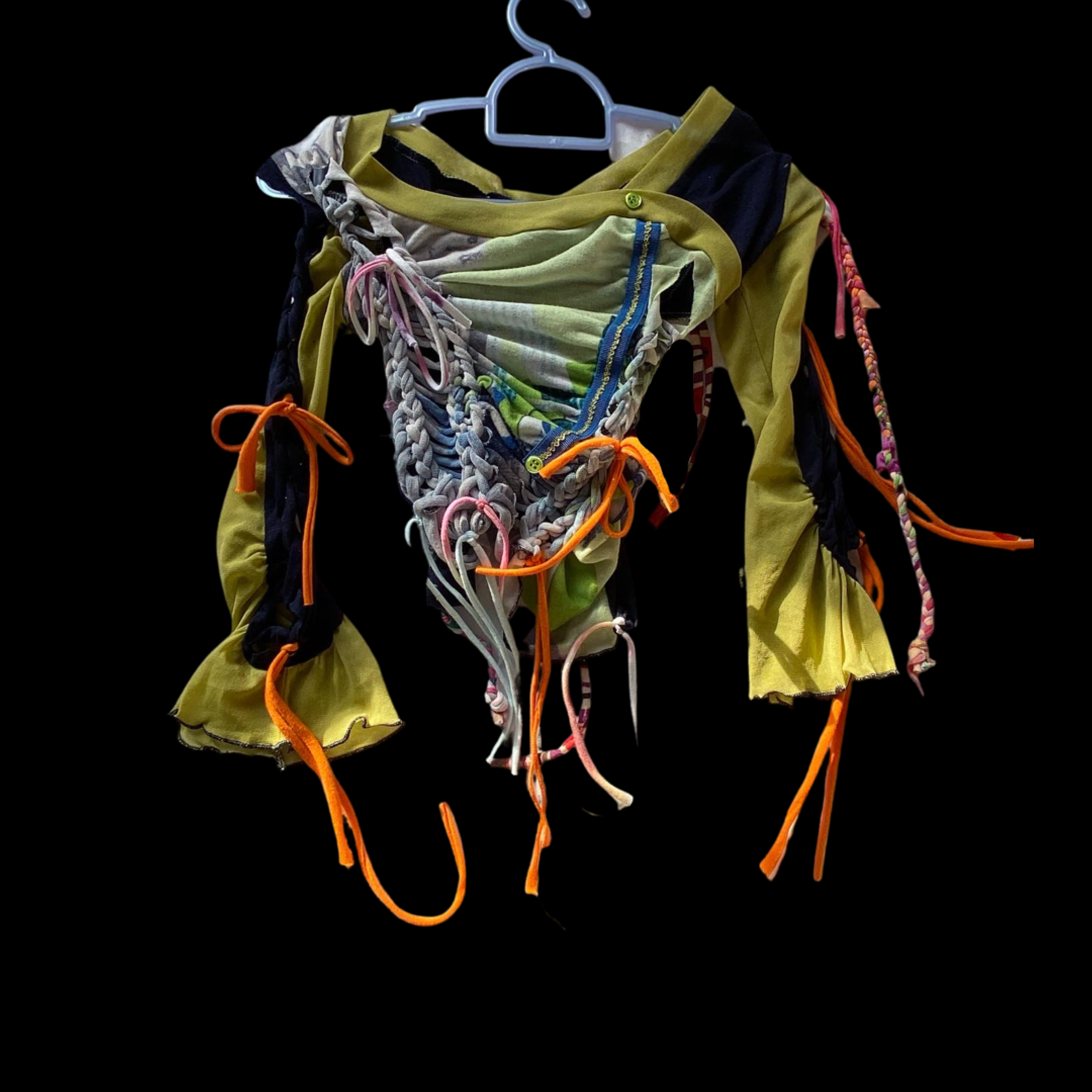 Colorful, patchwork-style jacket with various fabric textures, ribbons, and ties, displayed on a hanger against a black background.