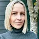 A woman with short blonde hair in a grey sweater 