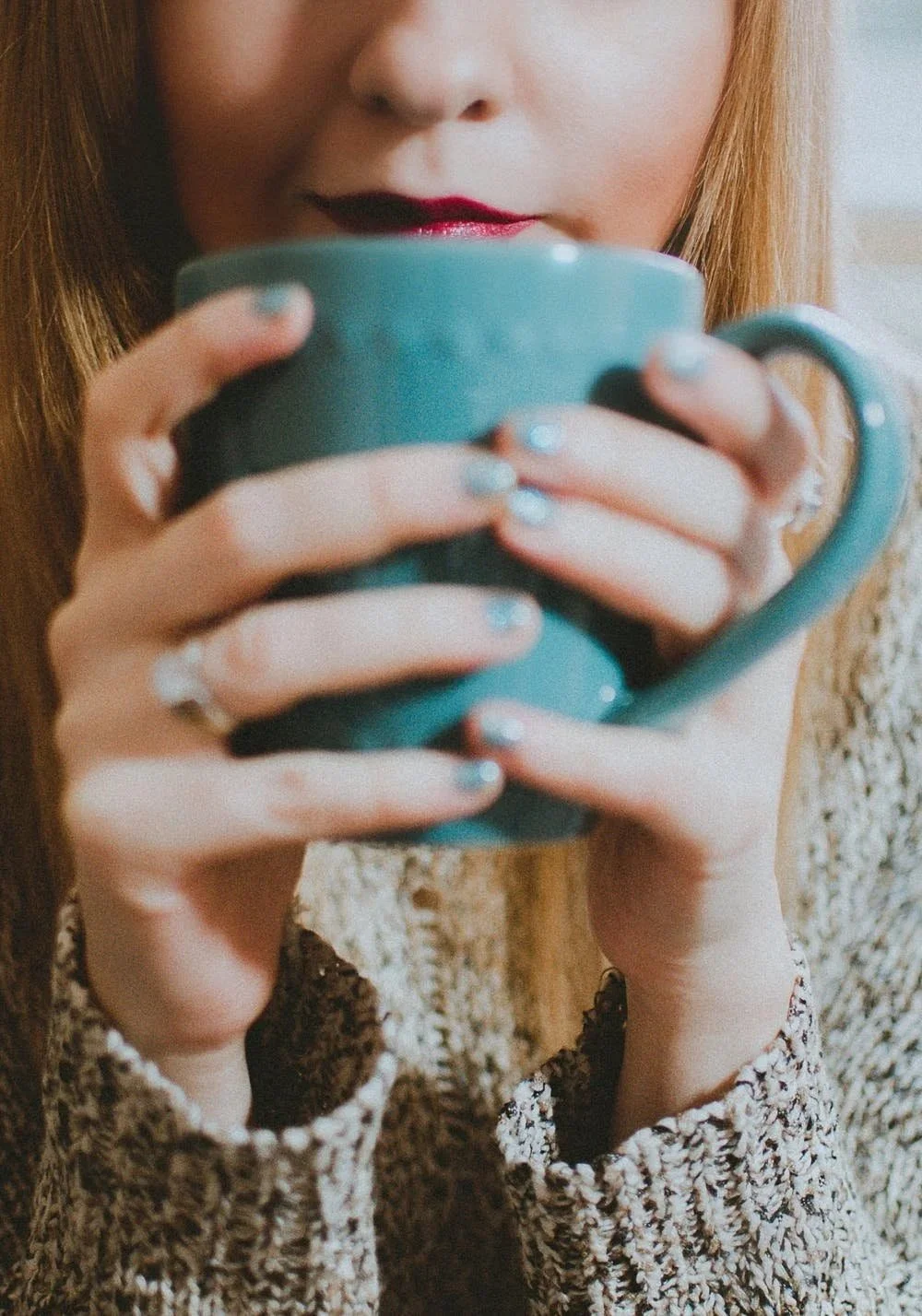 Wellness practitioner searching for free business tools while drinking coffee out of a blue mug and wearing red lipstick
