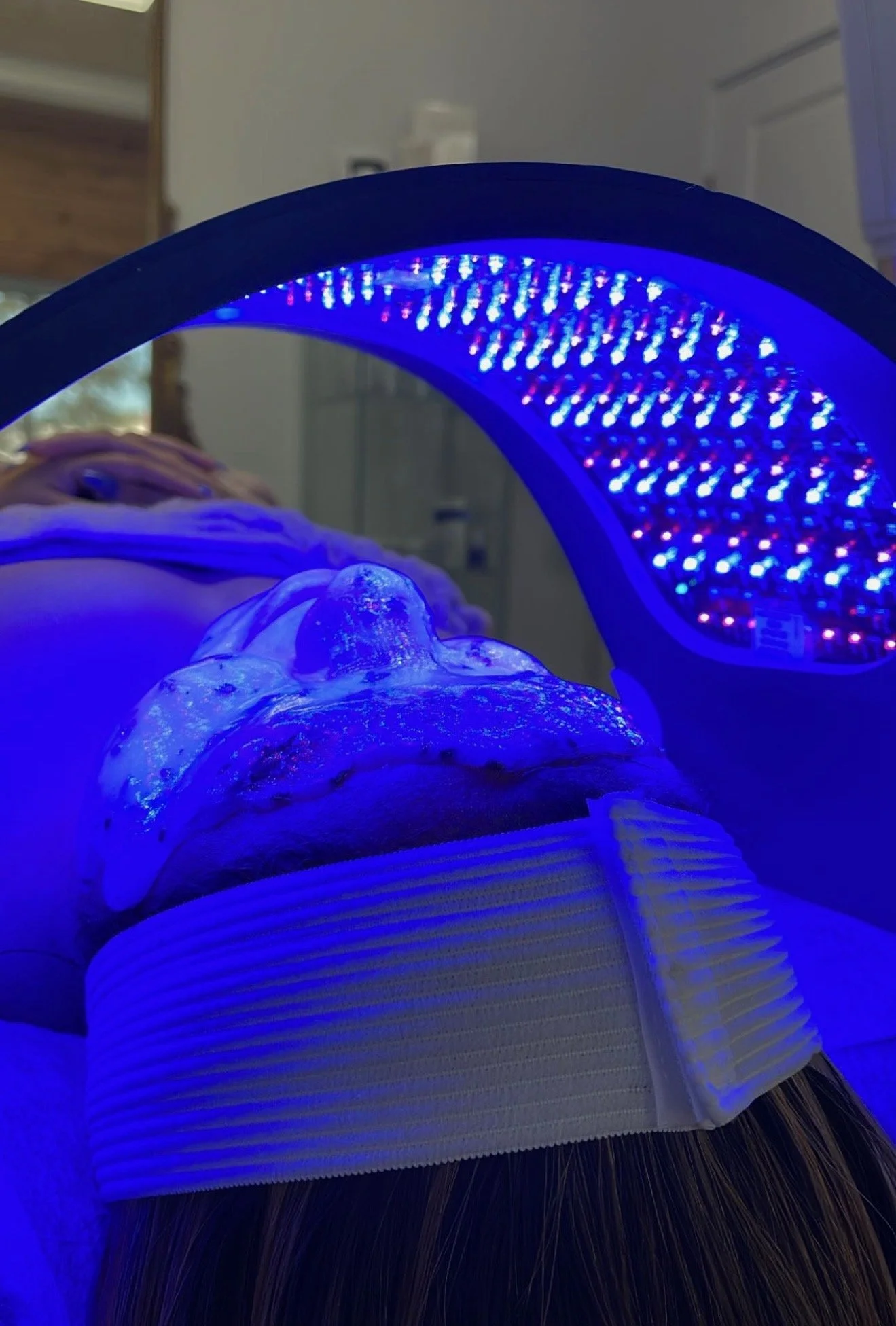 Person receiving LED light therapy with face mask