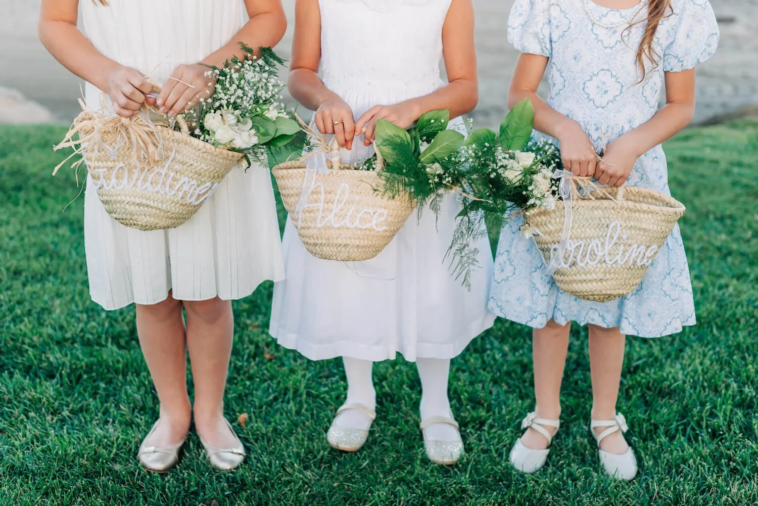 Three flower girls holding their baskets with white flowers and greenery.jpg