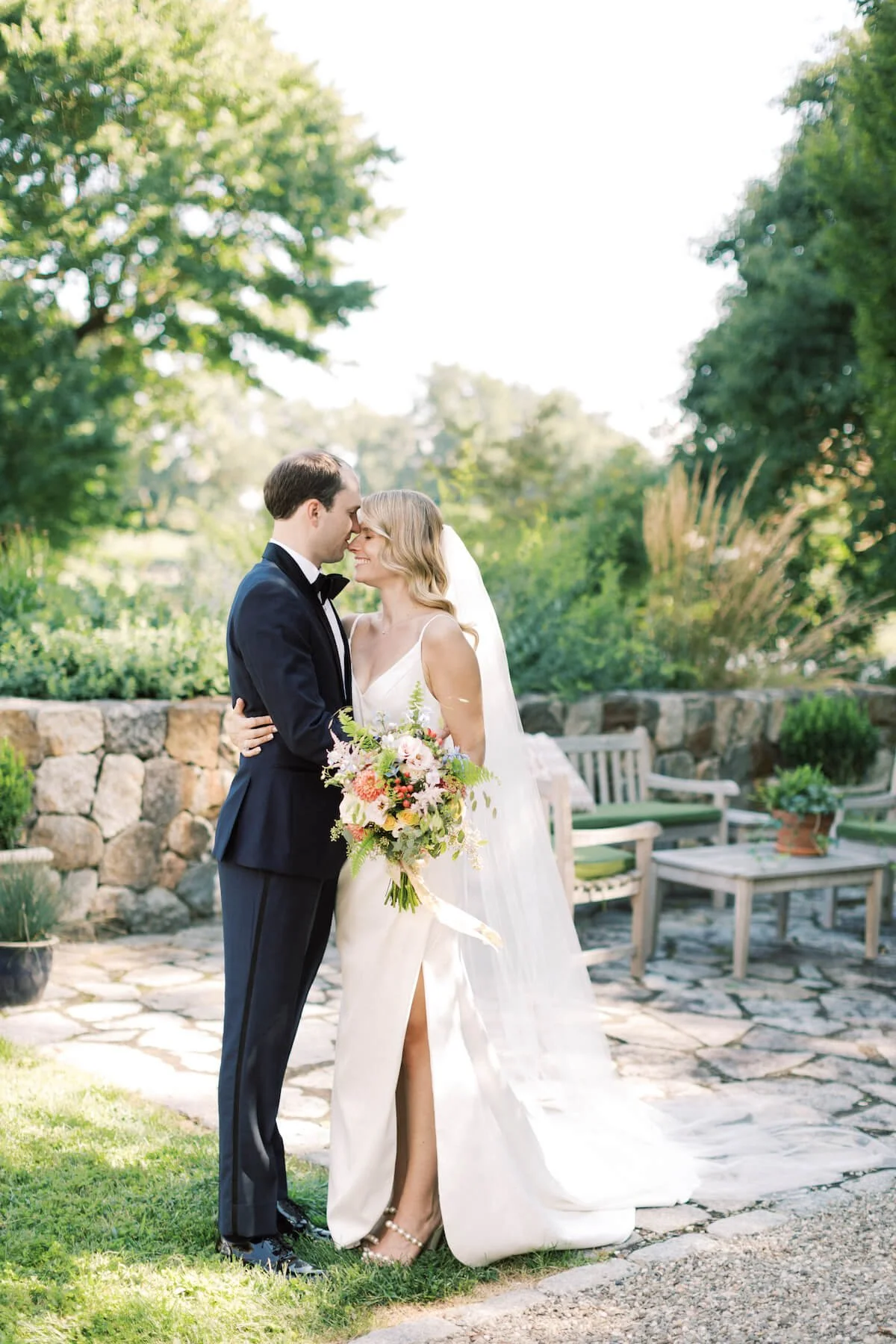 A bride holding her bouqet and leaning in tot he groom for a hug on an outdoor patio.jpg