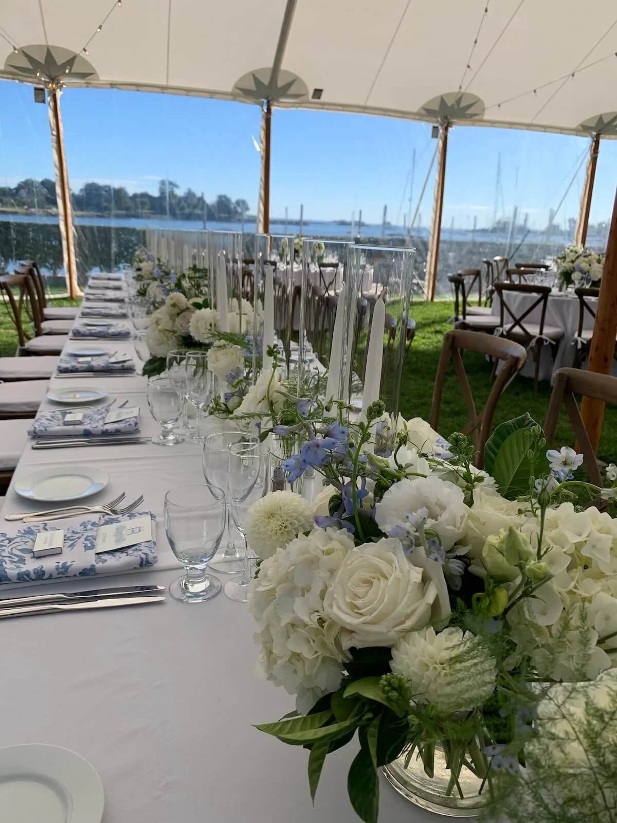 View of a long wedding party table with white floral arrangements overlooking a lake.jpeg