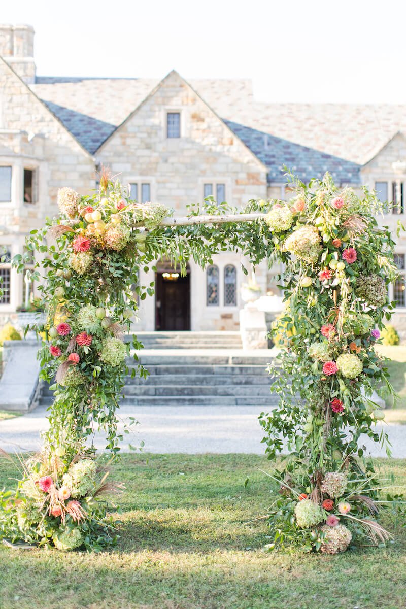 Wedding arbor bursting with flowers in reds, oranges and creams.jpg