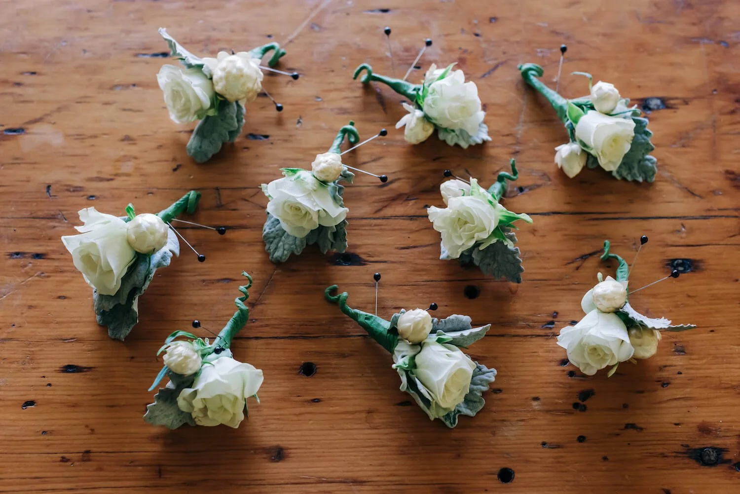 White rose boutonneires on a wooden table.jpg