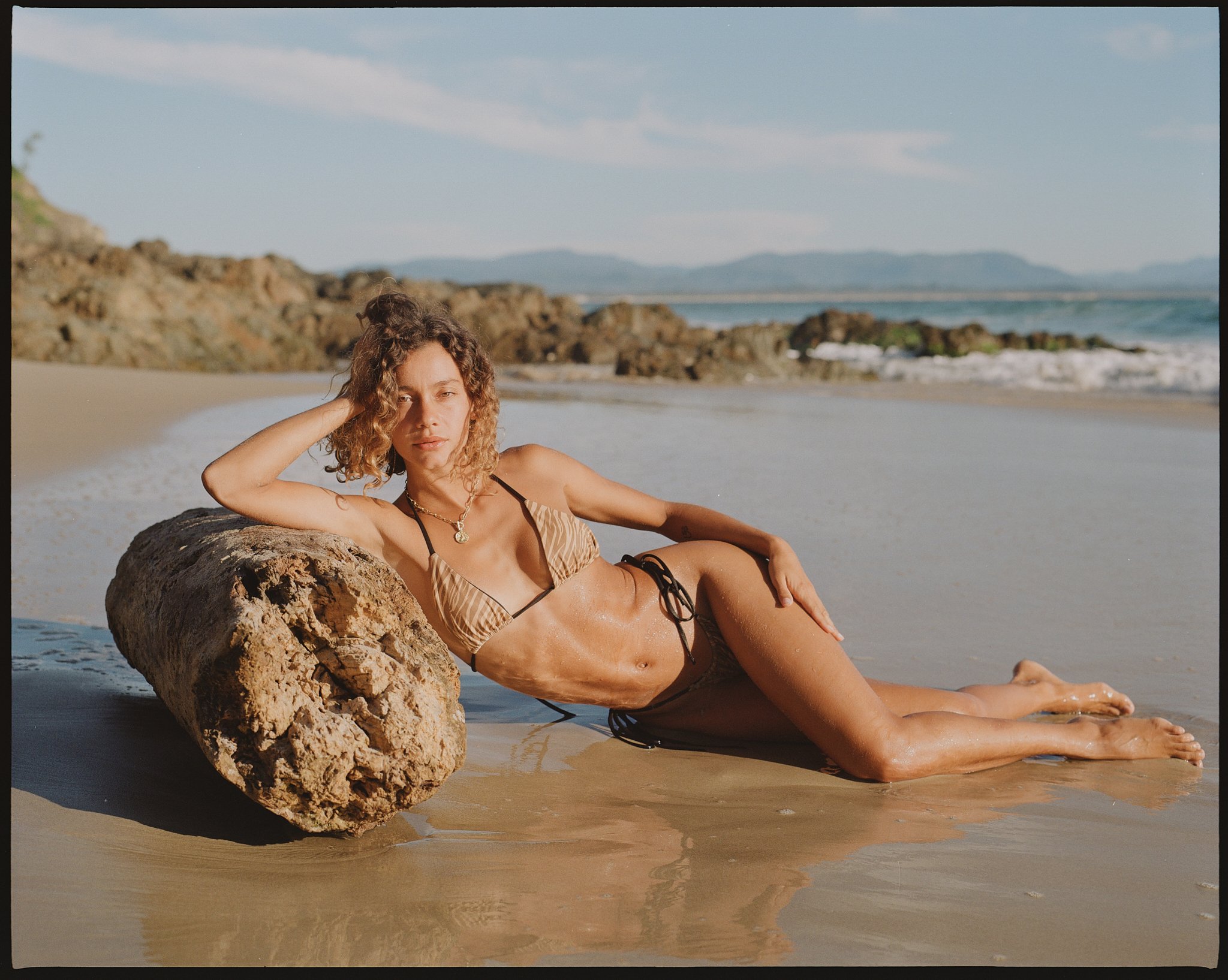 Coastal swimwear campaign image with relaxed beach styling.
