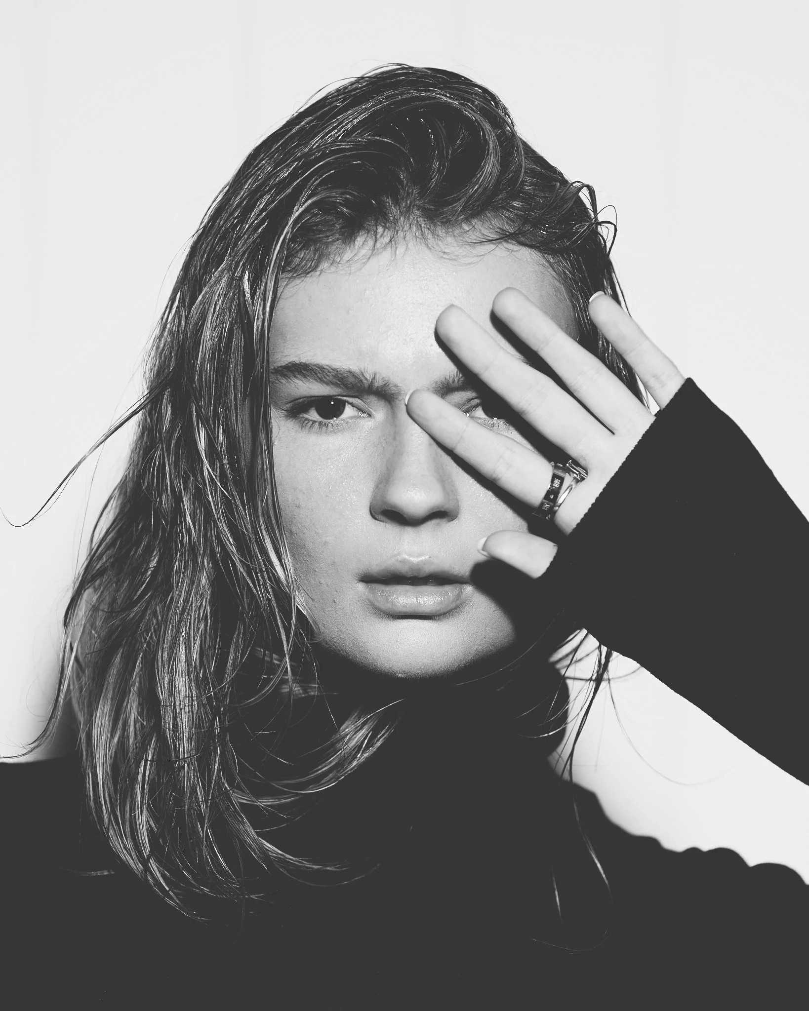 Black and white editorial beauty portrait with wet hair and dramatic close-up styling.
