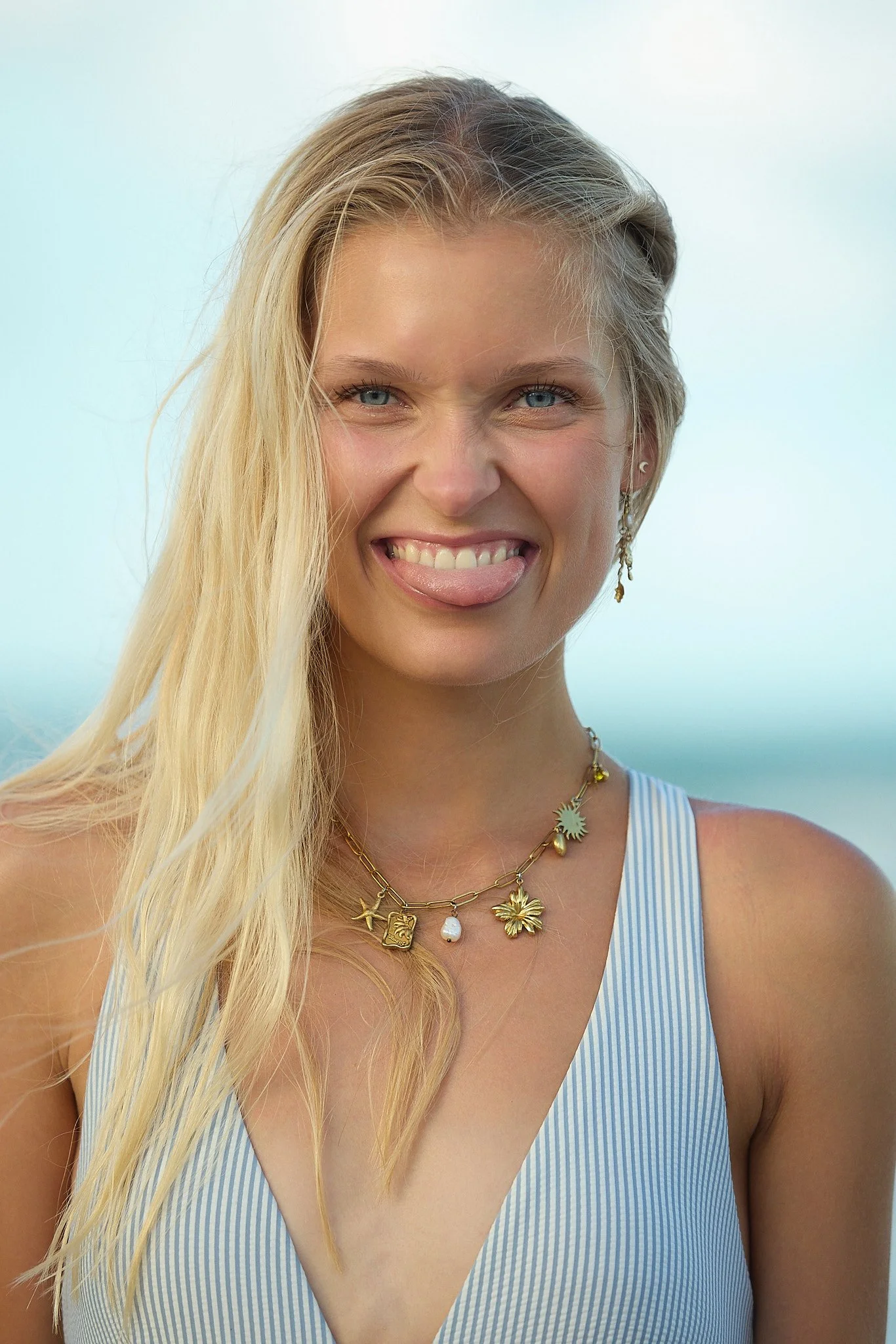 Natural light beauty portrait with a relaxed smile and coastal summer styling.