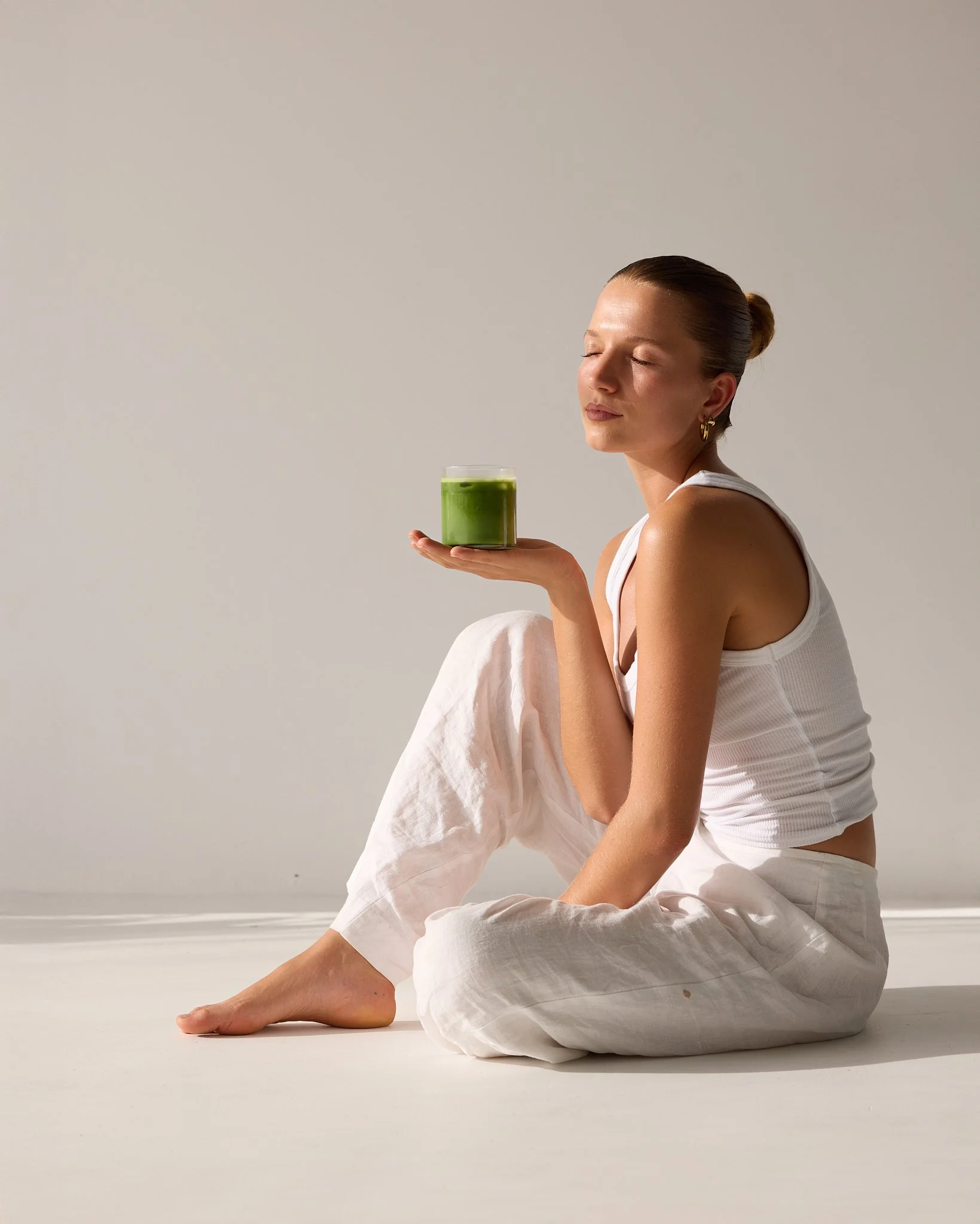Model relaxing with eyes closed holding matcha in warm natural light – editorial lifestyle photography Byron Bay