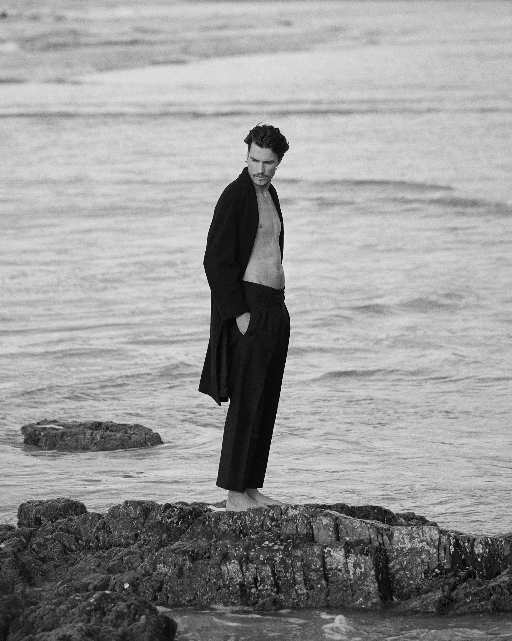 Elegant menswear portrait of a man in a coat photographed on the beach.