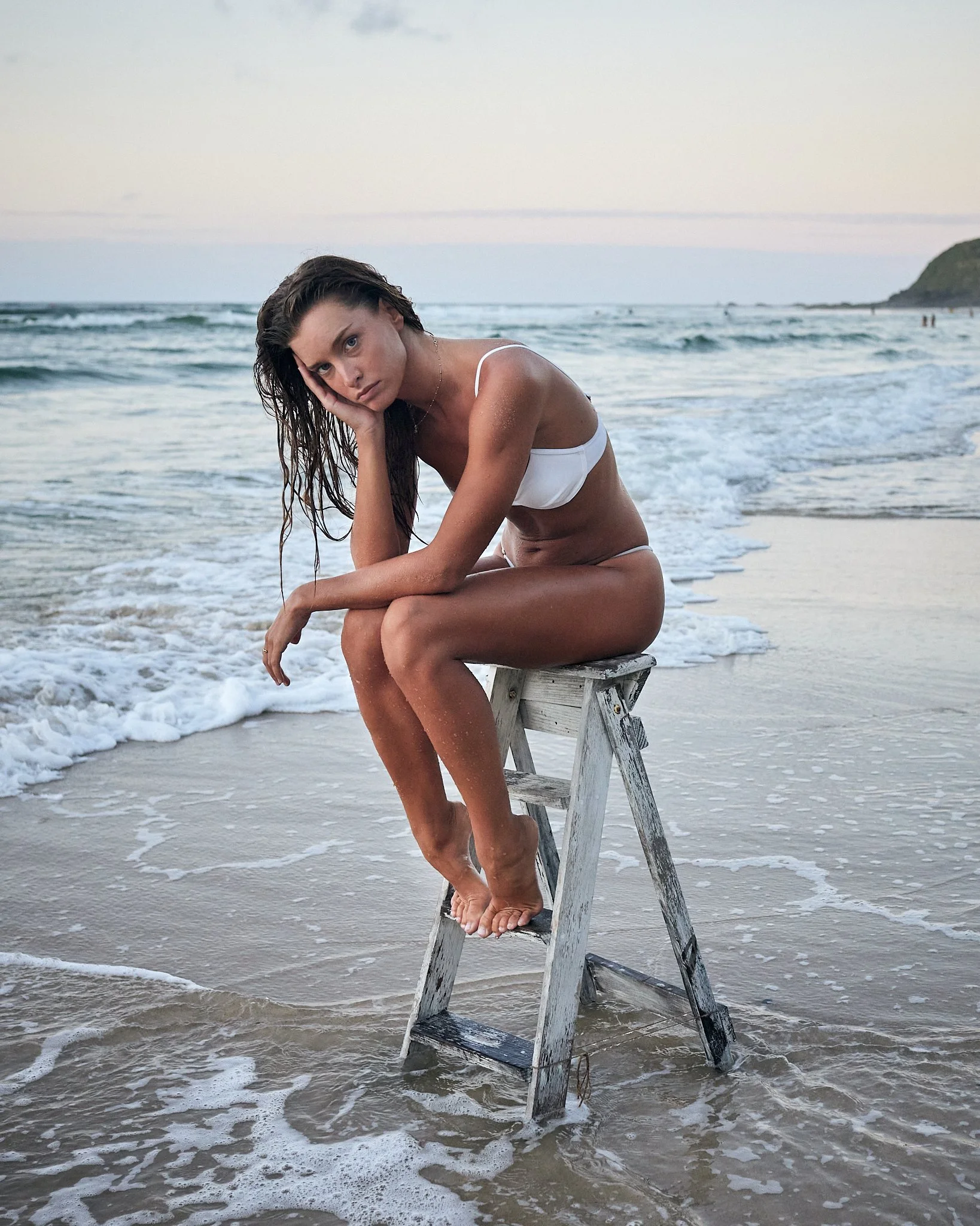 Swimwear editorial portrait of a woman in a white bikini photographed on the beach near Byron Bay.