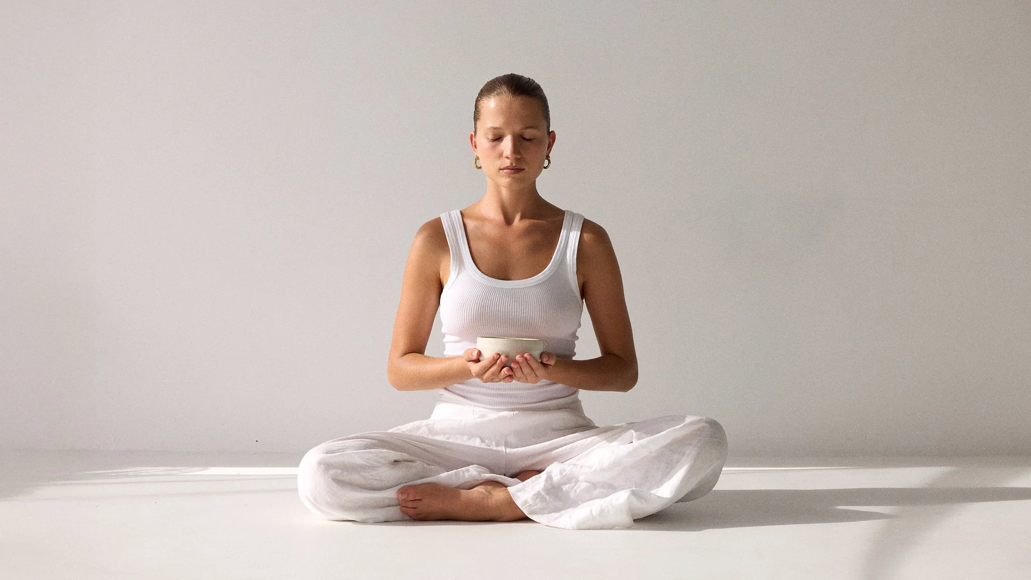 Model sitting in calm meditation pose with ceremonial matcha bowl – Byron Bay editorial lifestyle photography