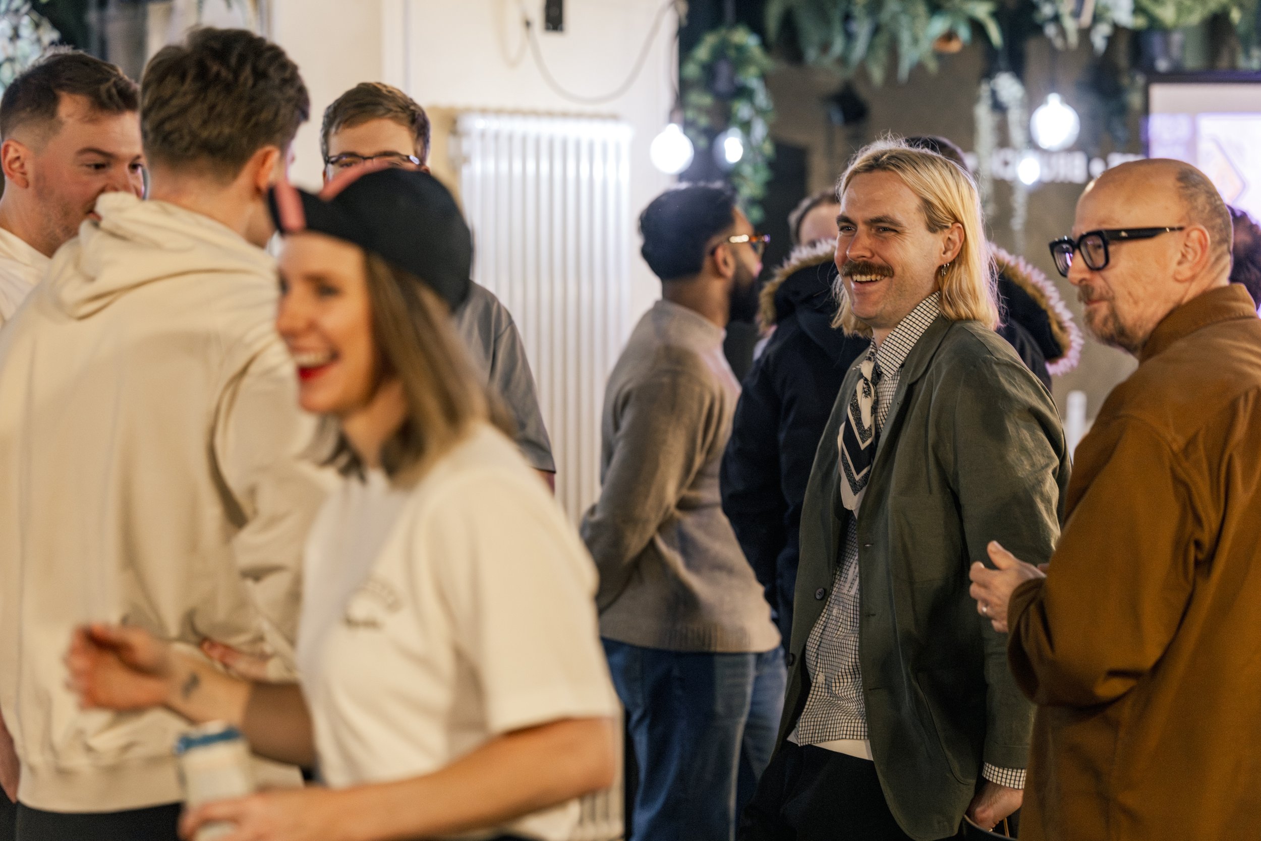 Candid event photography of guests laughing and networking at the Rapha Cycling Club Awards Night in Manchester, documenting the relaxed community atmosphere and social interactions.