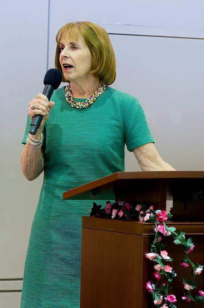 Woman in green dress speaking at podium with microphone
