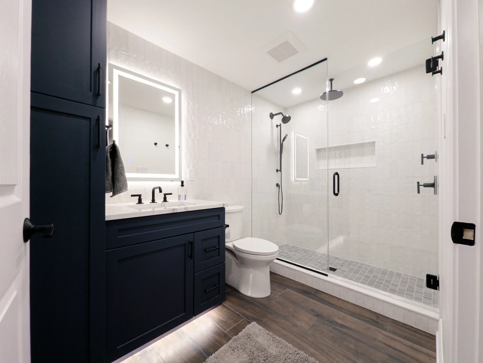 modern-basement-bathroom-navy-vanity-backlit-mirror.webp
