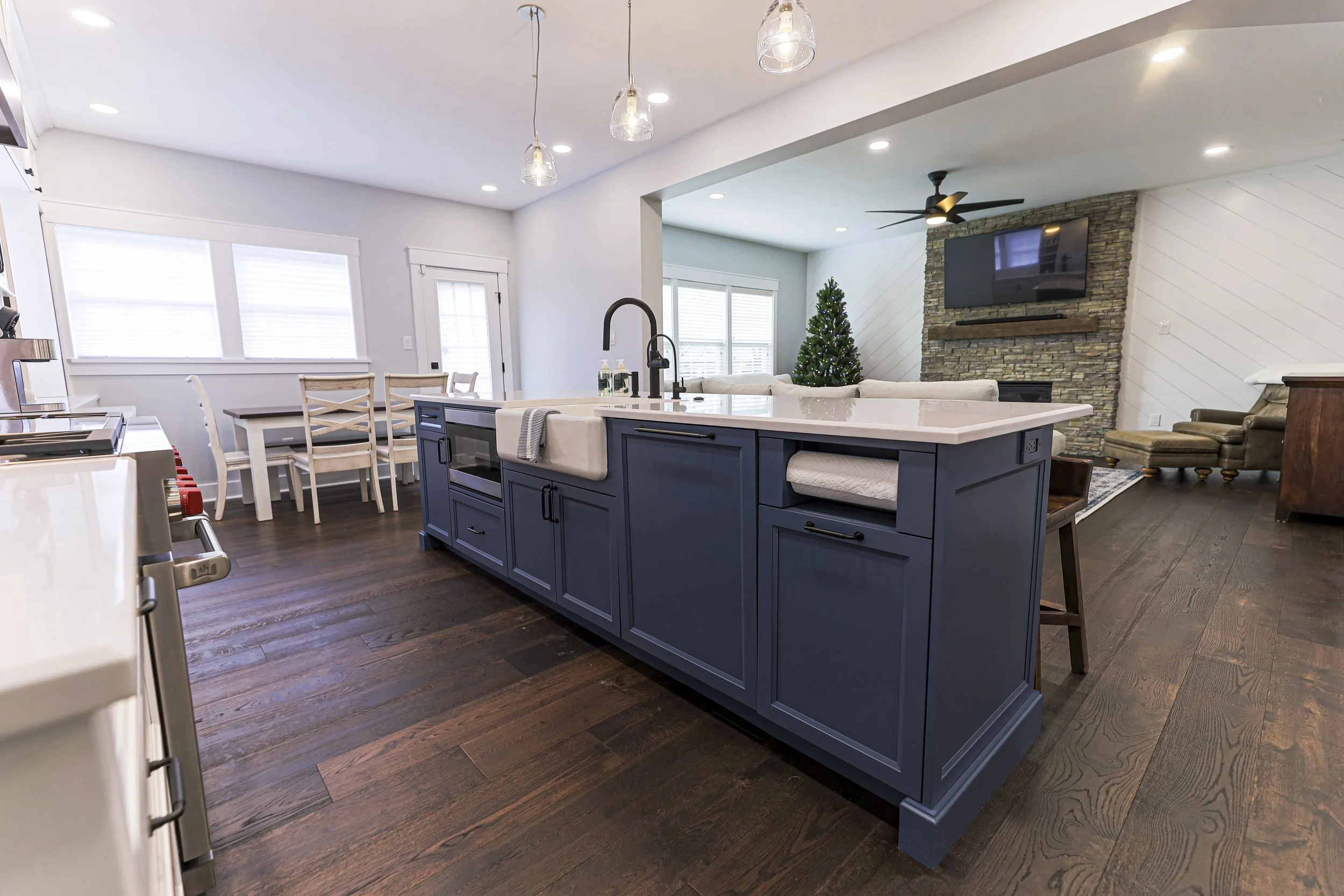 Navy kitchen island with farmhouse sink open to the dining area and family room