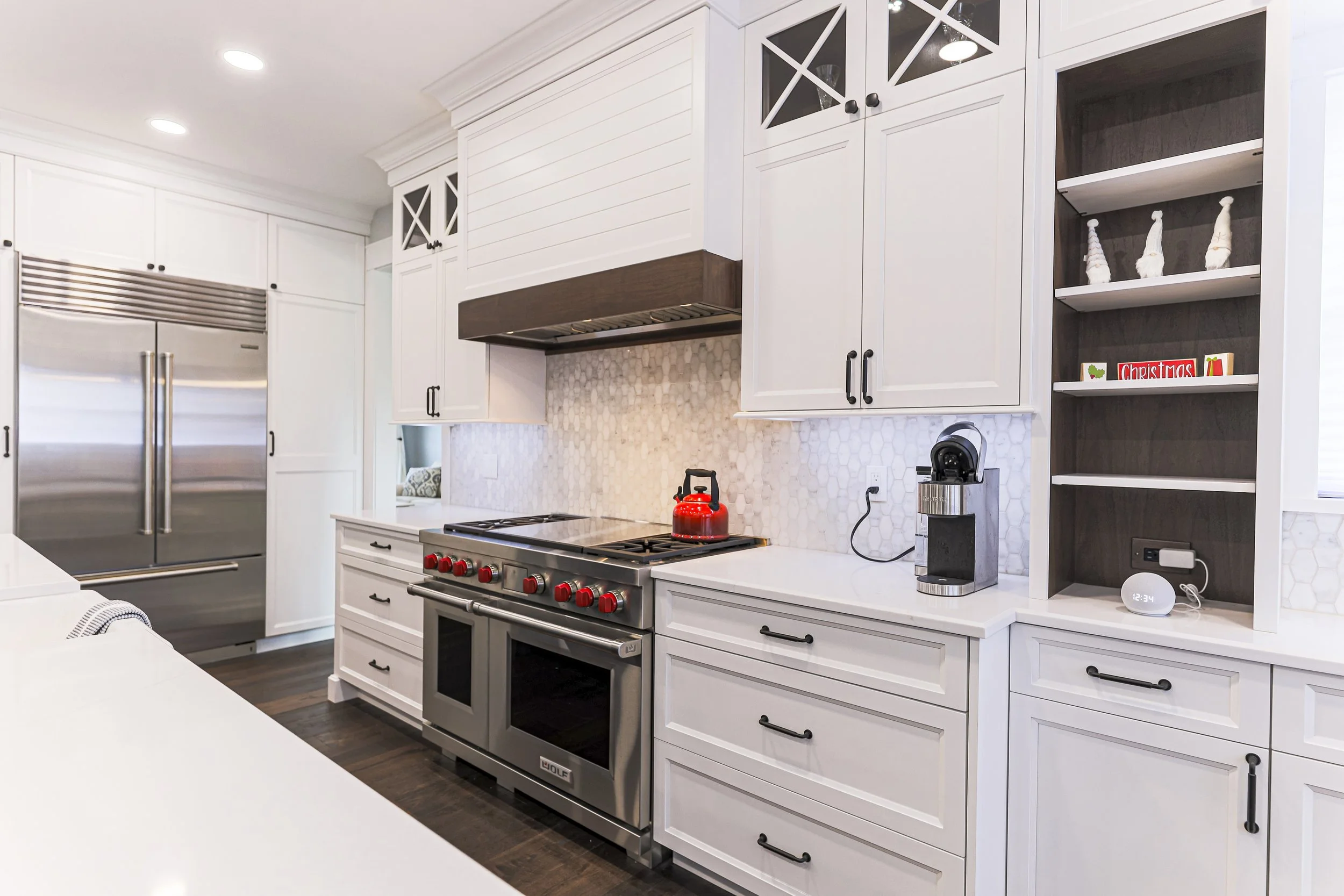 Professional range under a wood-trimmed hood with built-in refrigerator and open shelving