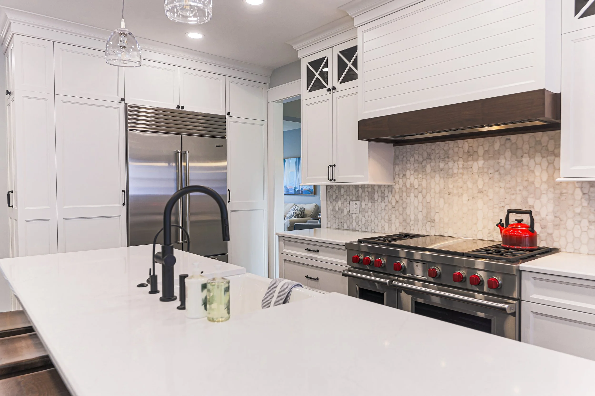 White quartz island with matte black faucet facing the range wall and built-in refrigerator