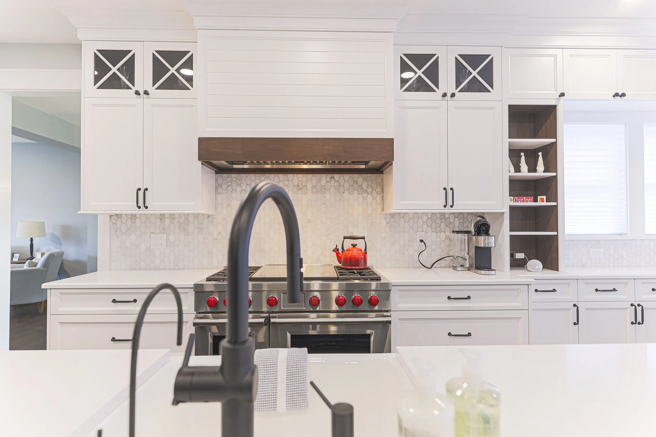 Matte black faucet on a quartz island with the professional range and shiplap hood beyond