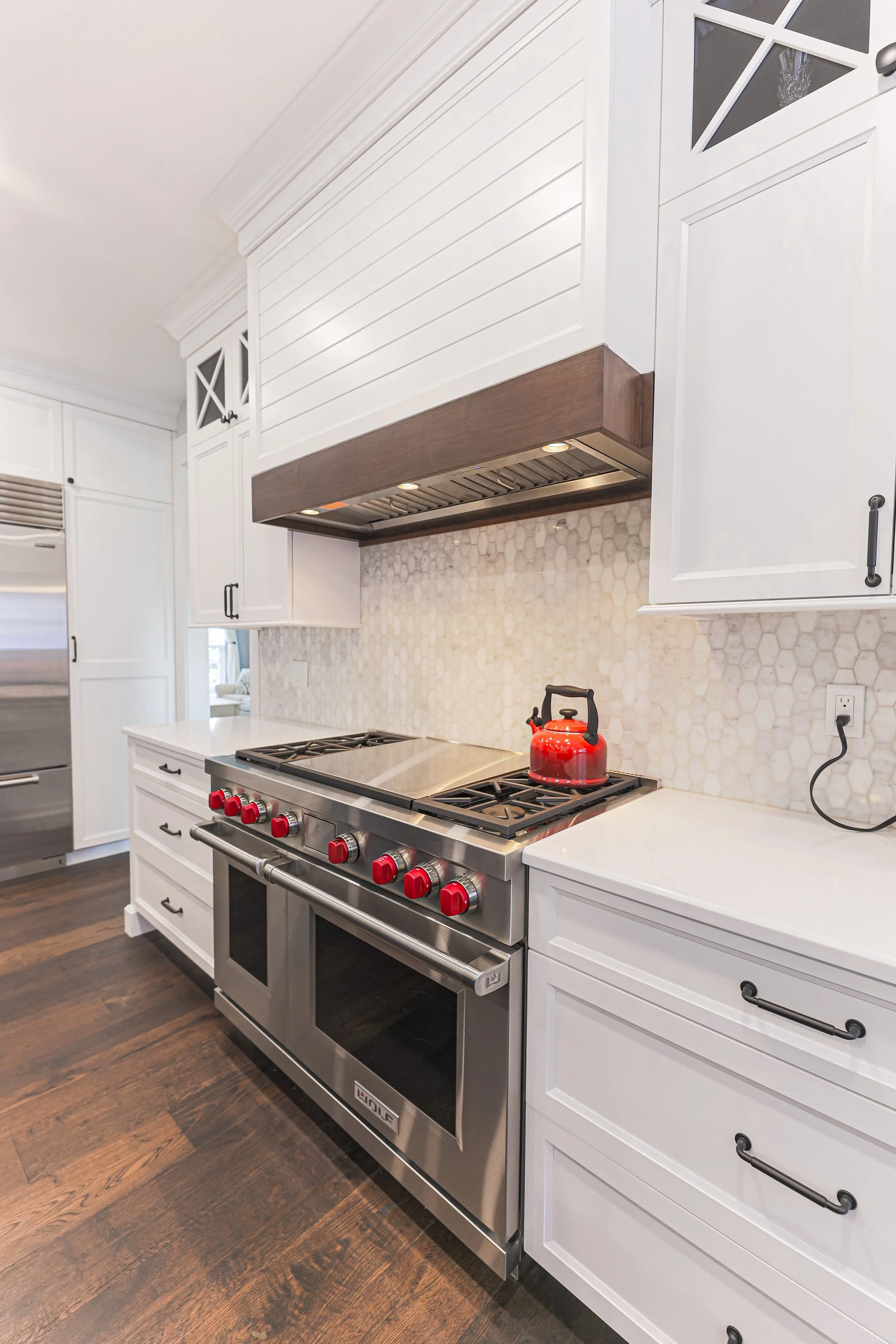 Professional gas range with red knobs beneath a shiplap range hood