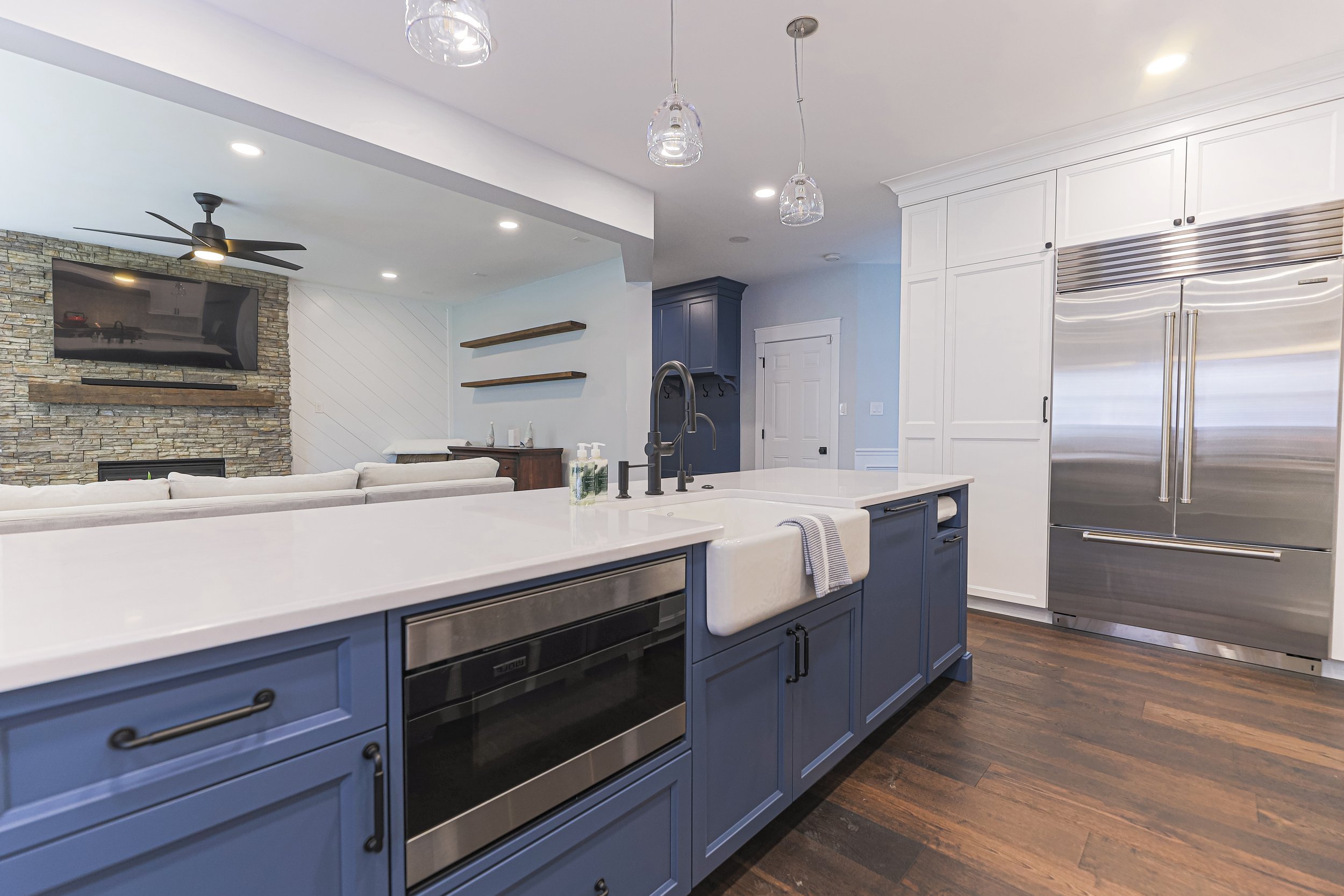 Navy island with farmhouse sink beside a stainless built-in refrigerator