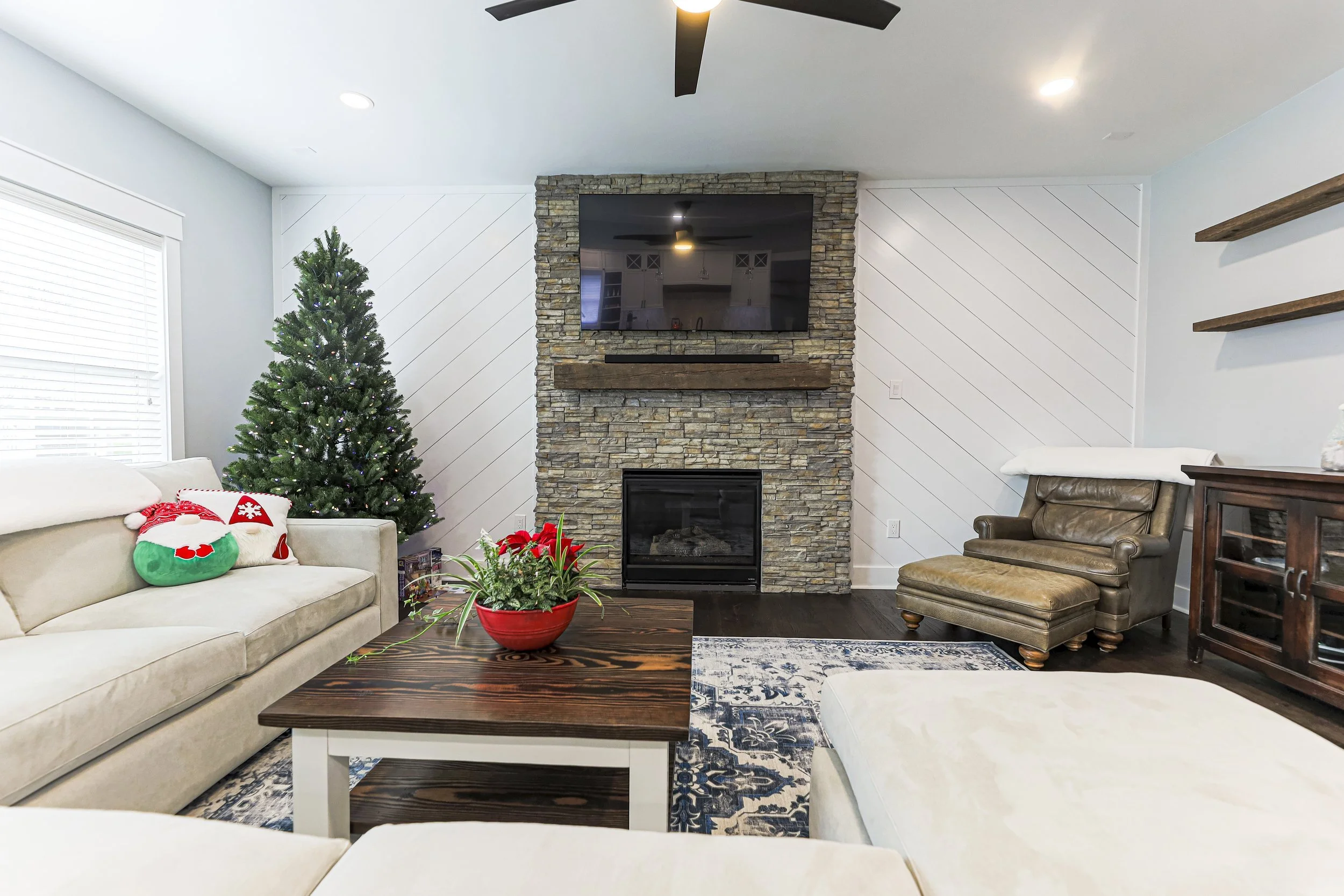 Open family room with stone fireplace, diagonal shiplap accent wall and sectional sofa