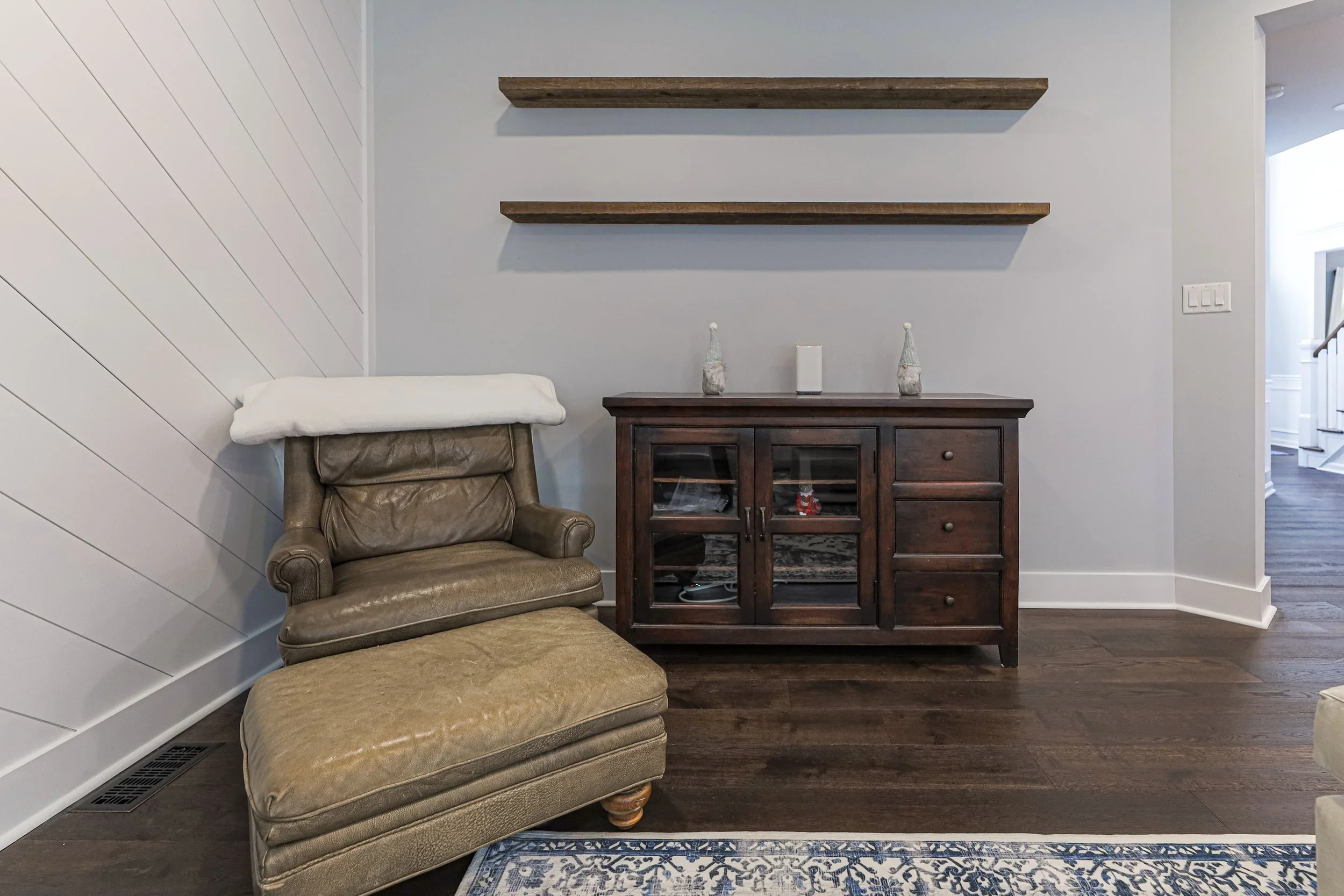 Family room reading corner with leather chair, floating shelves and wood console