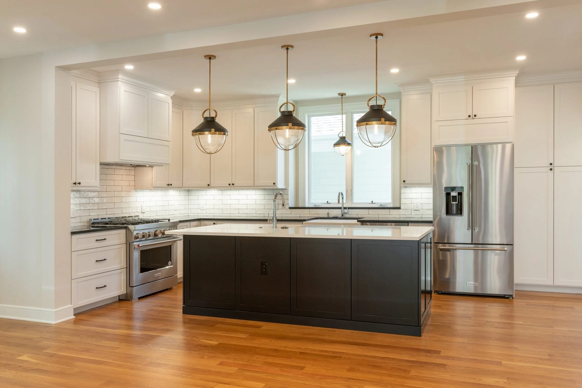 New construction kitchen in Chestnut Hill with espresso island, white cabinets and lantern pendants