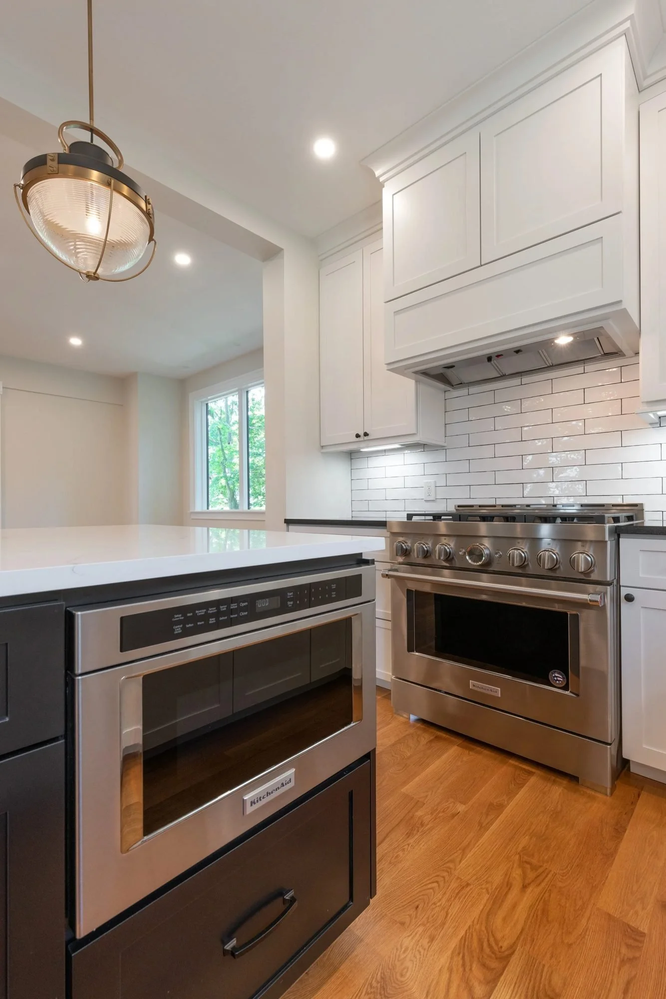 Microwave drawer in the island facing a stainless range and subway tile