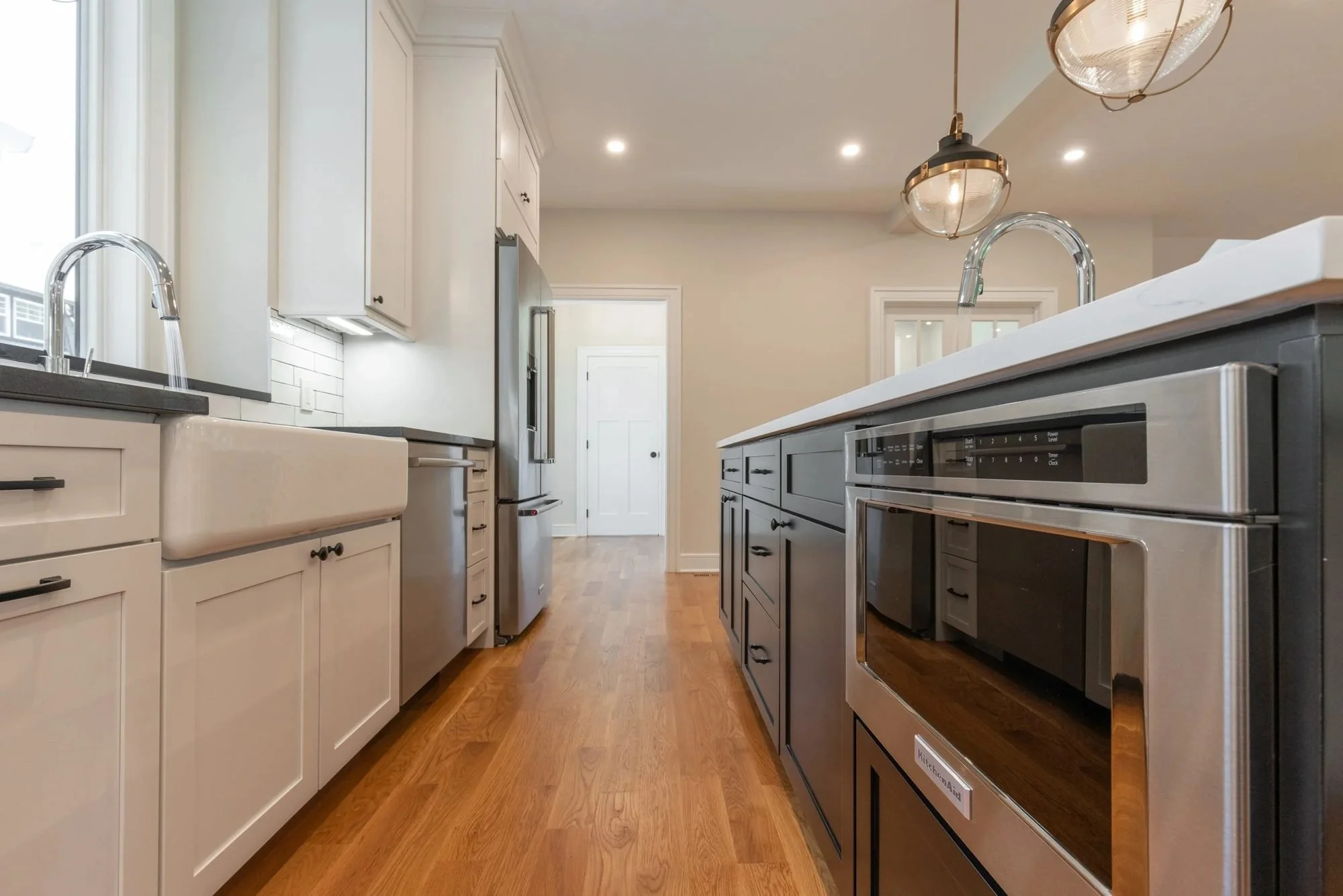 Farmhouse sink and island microwave drawer in a white kitchen