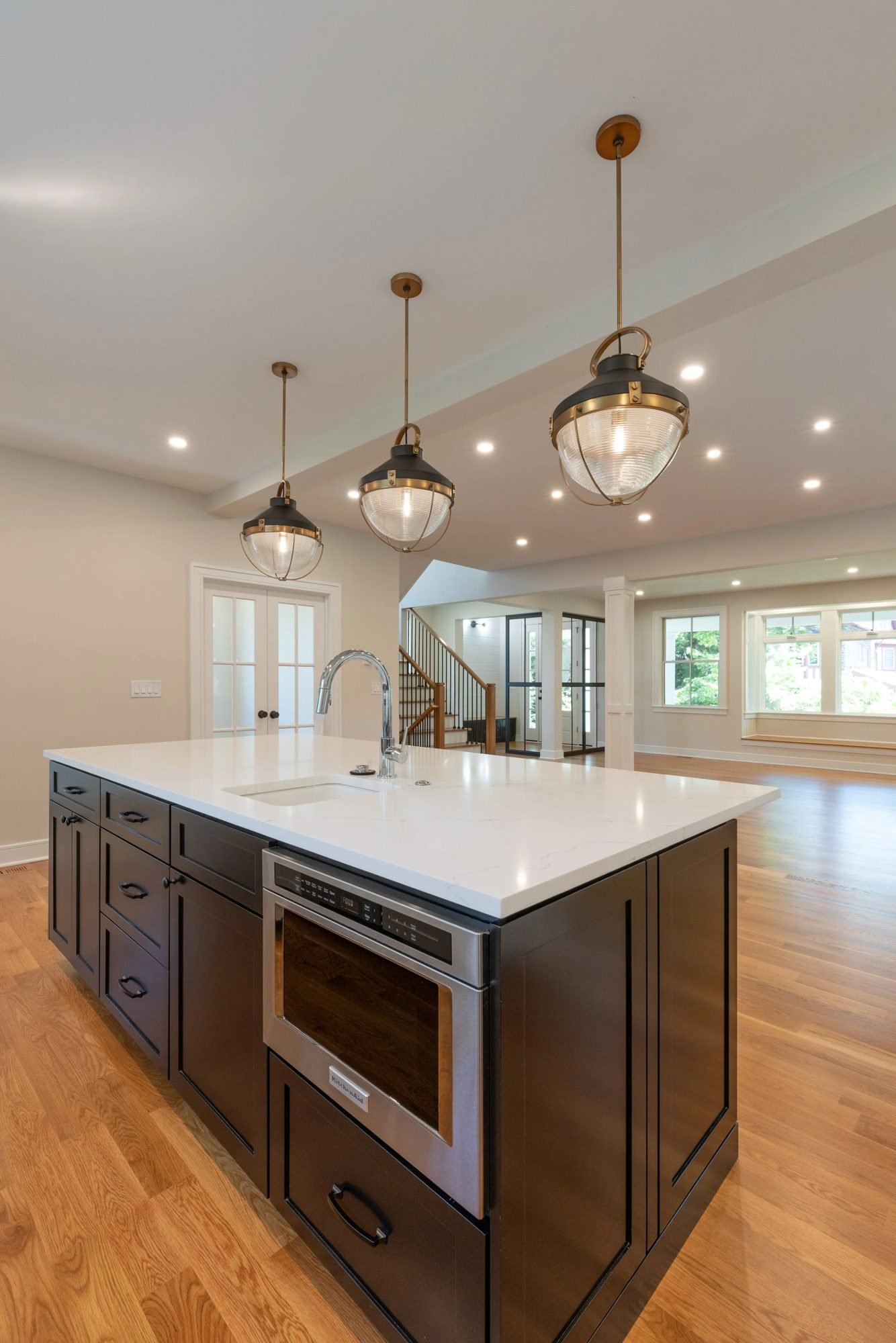 Dark kitchen island with three pendants in an open floor plan