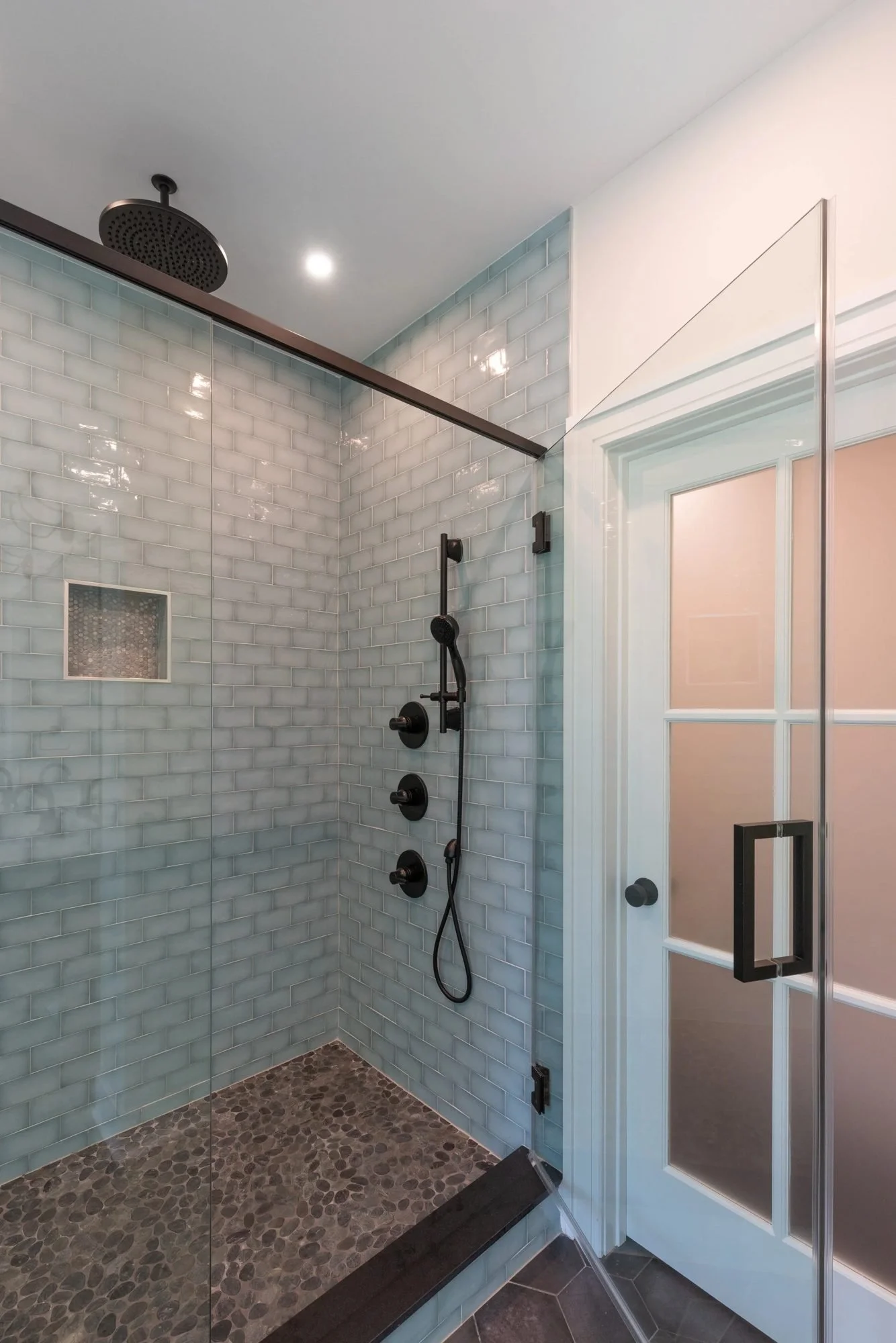 Walk-in shower with pebble floor and black rain shower head