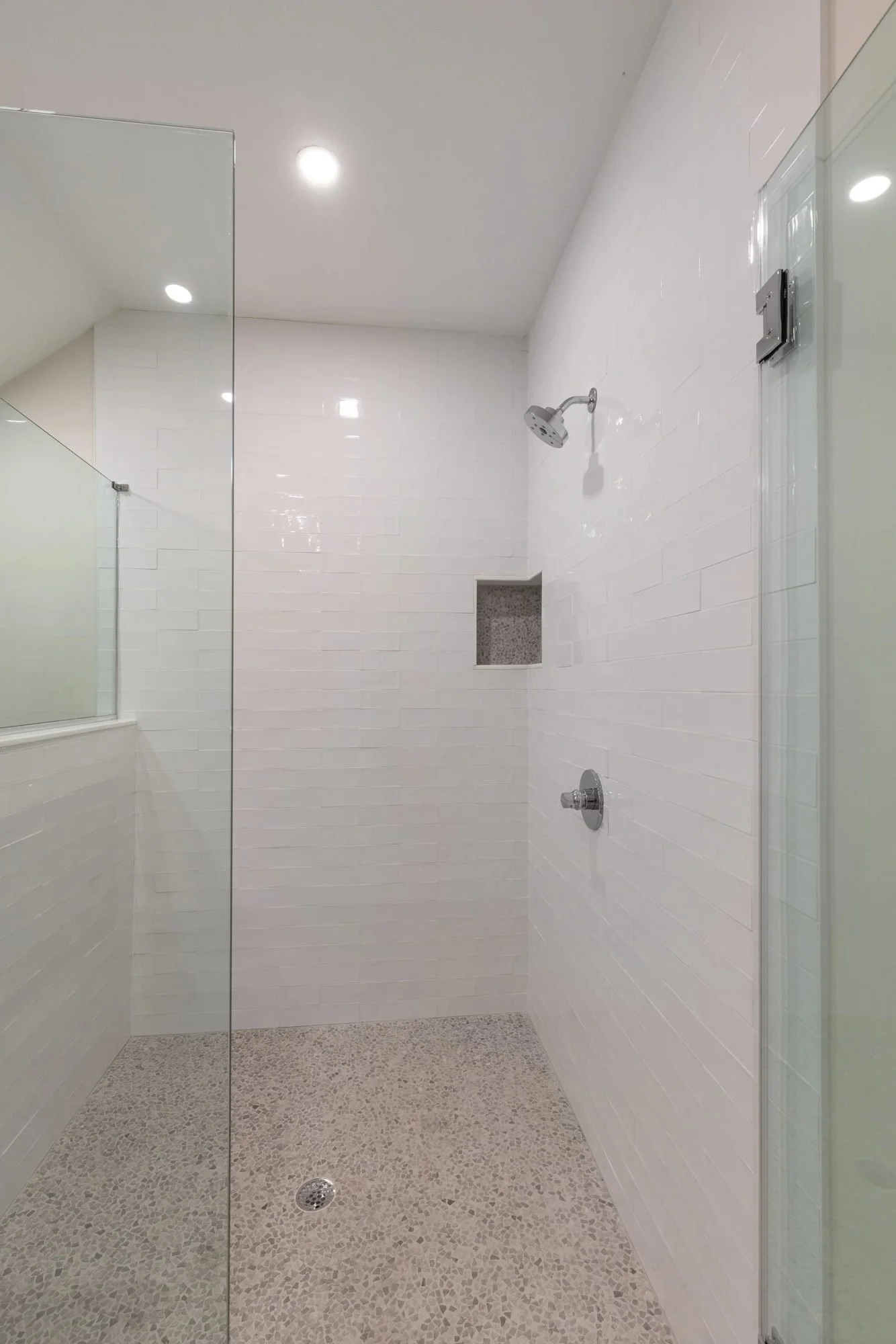 Frameless glass shower with white tile and recessed niche