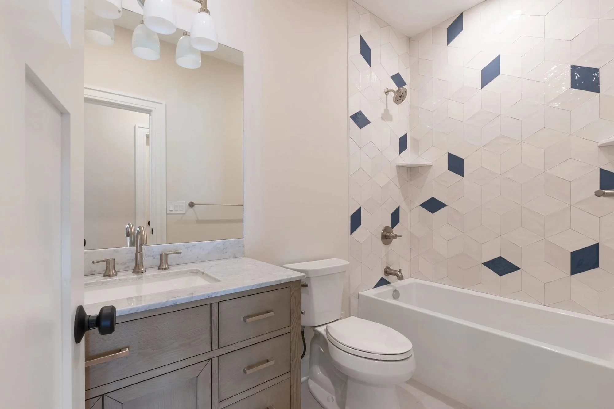 Hall bathroom with gray vanity and patterned tile tub surround