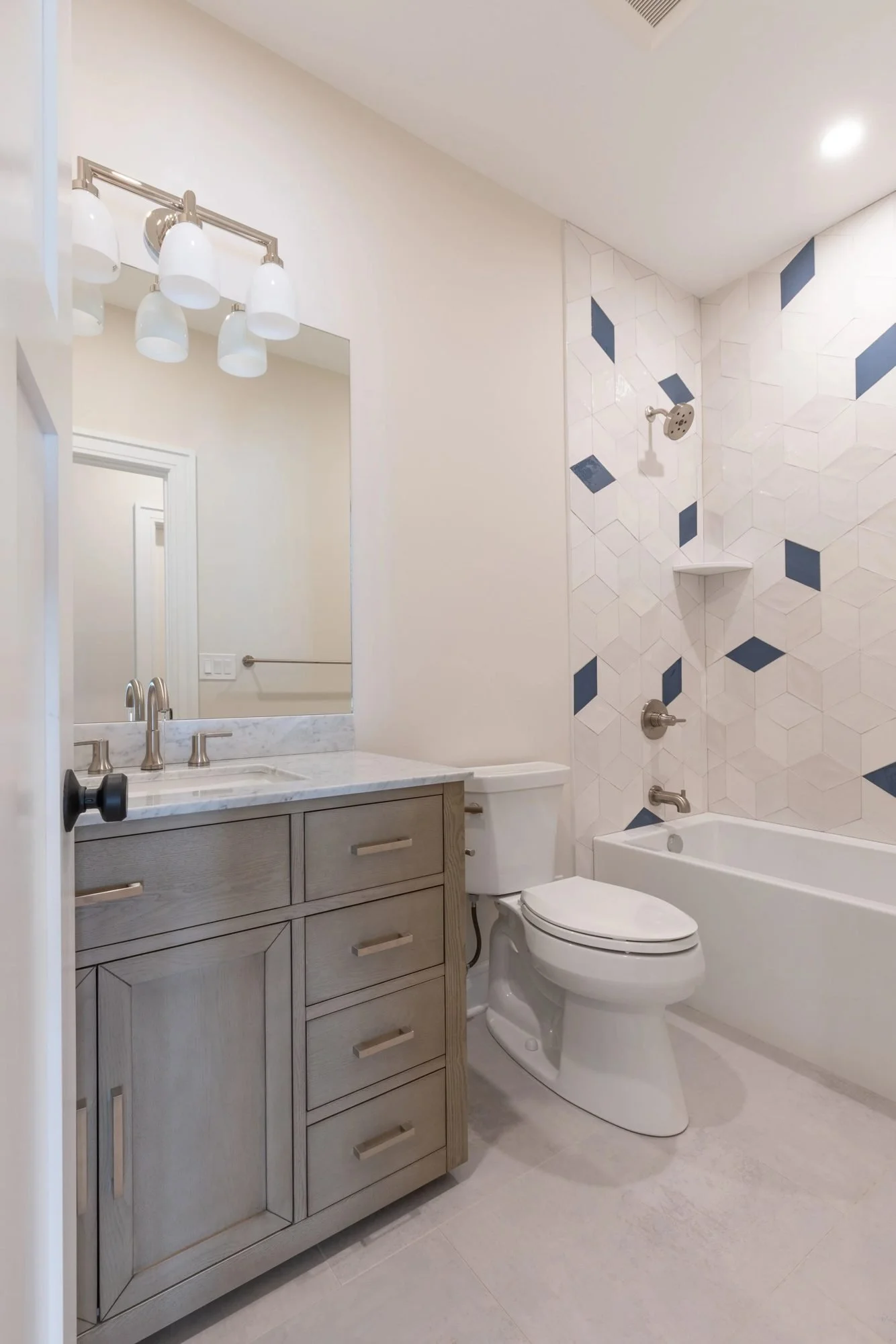 Hall bathroom with gray vanity, toilet and tub-shower