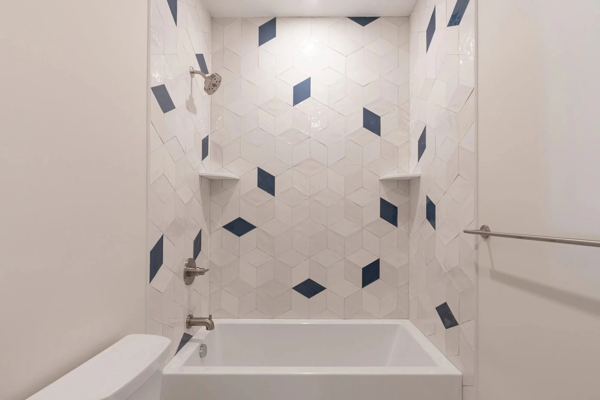 Alcove bathtub with white and navy patterned tile surround