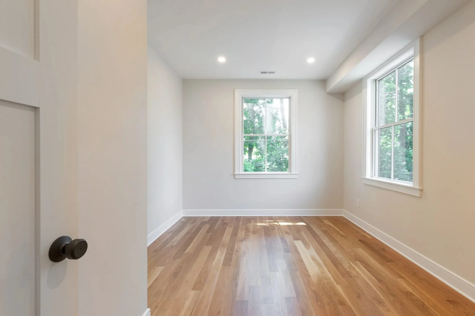Bedroom with hardwood floors and two windows