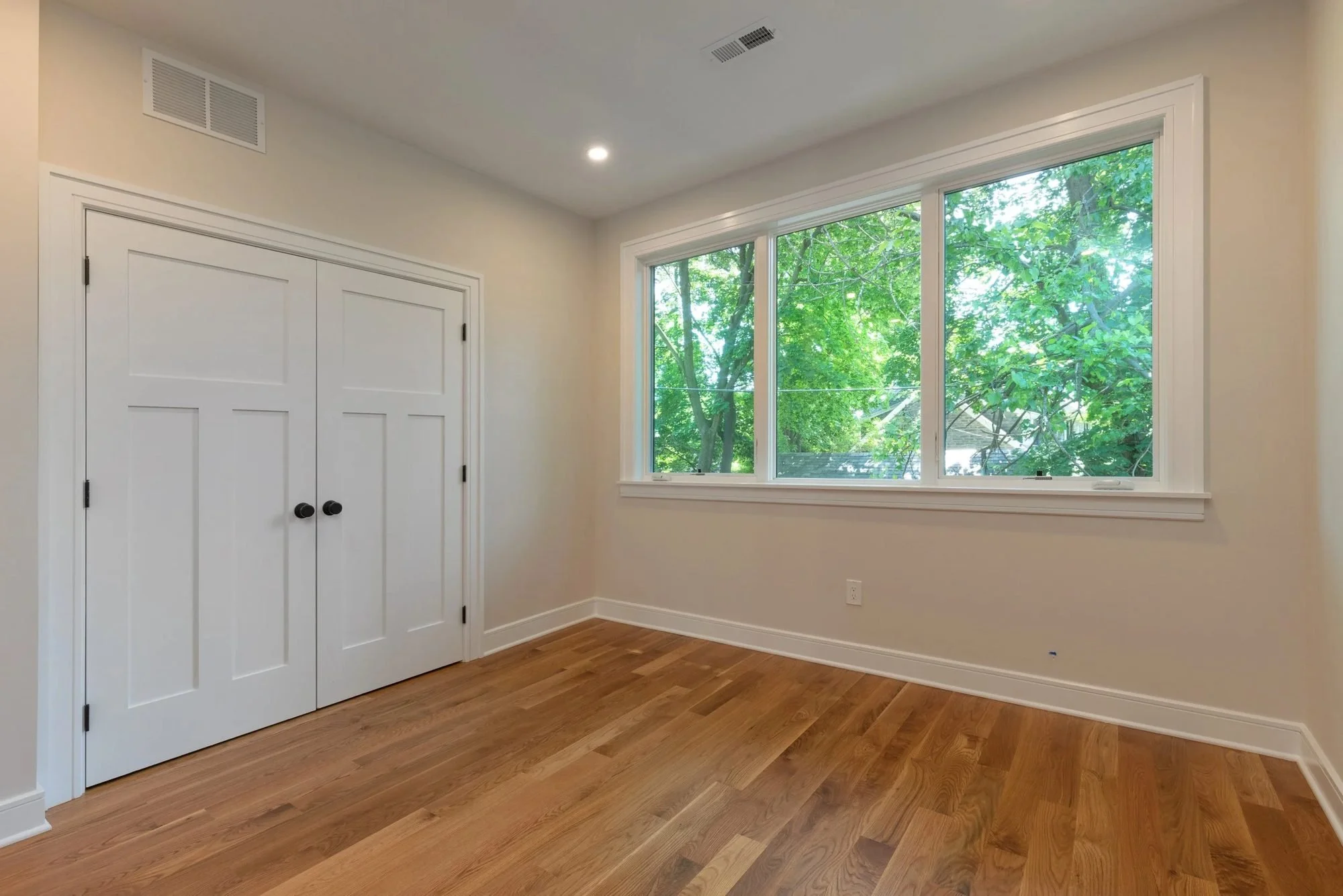 Bedroom with double closet doors and a large picture window
