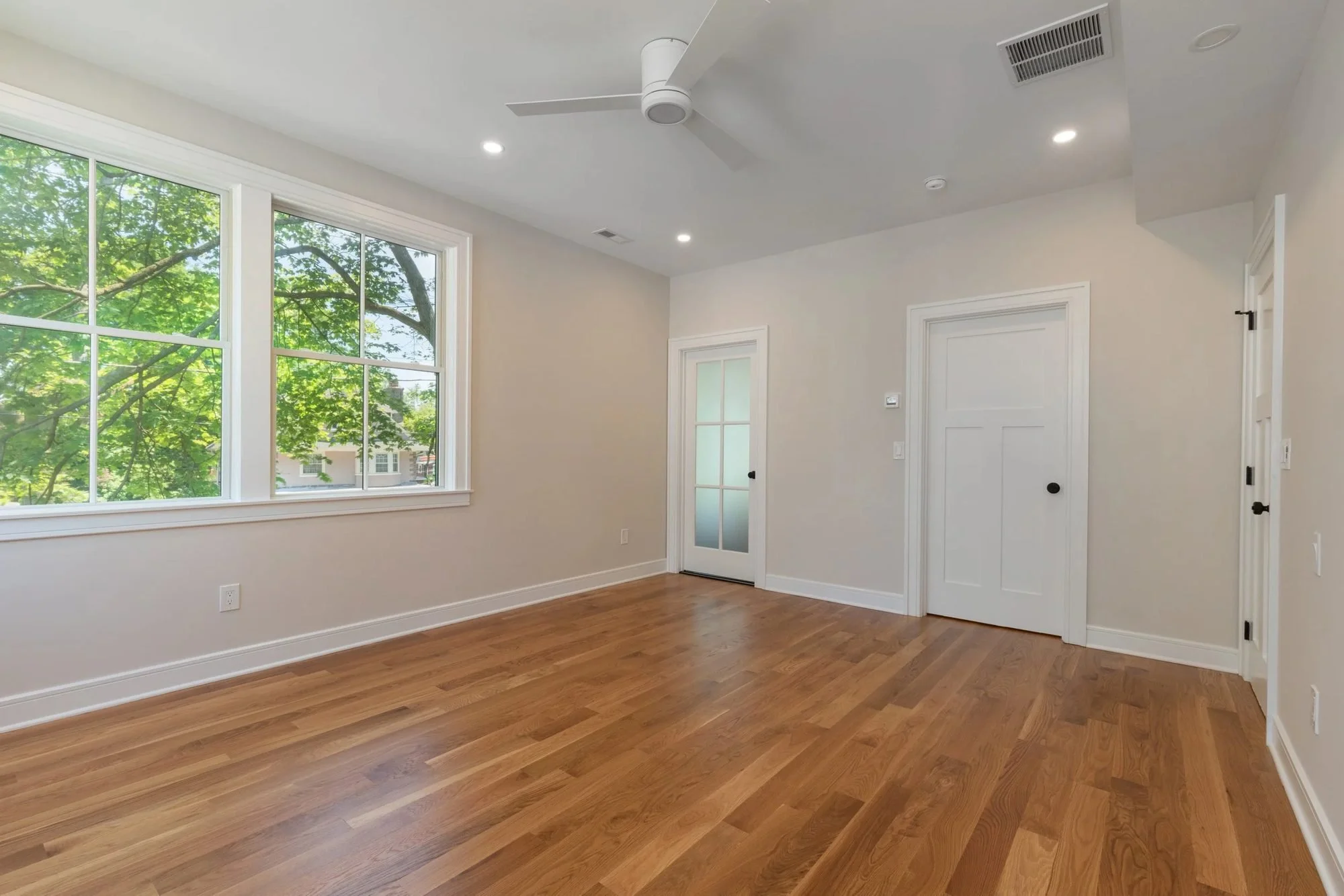 Primary bedroom with ceiling fan and oak floors